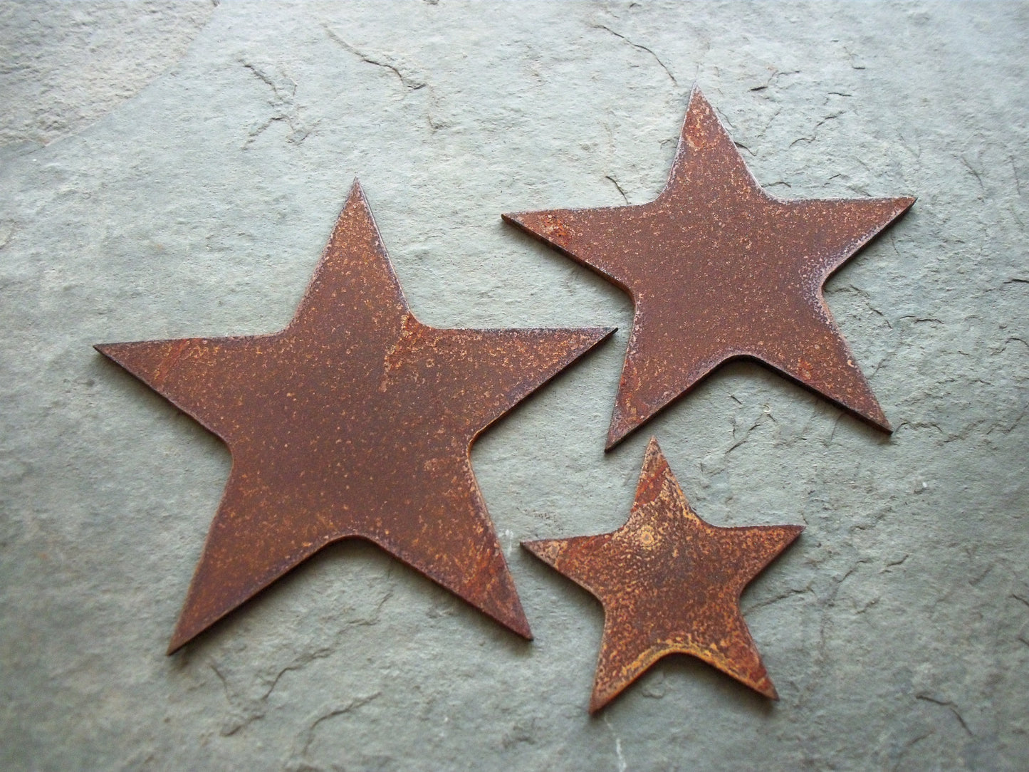 Rustic metal lucky stars set garden decor on a grey base, 3 different sized rusted steel stars, unique garden art.