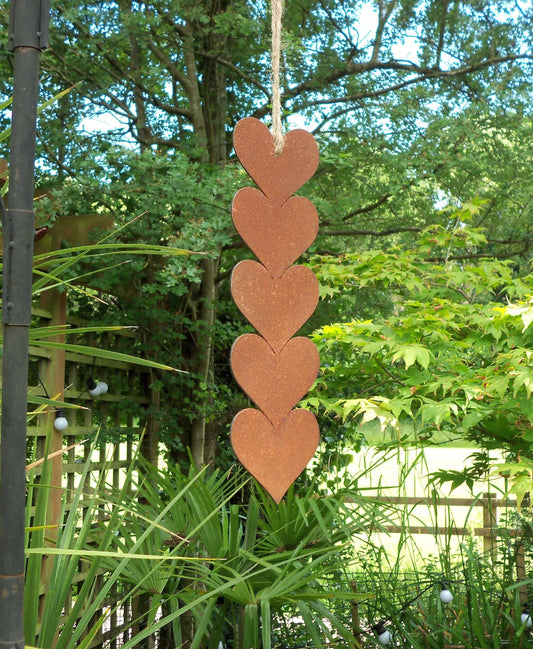 Rusty metal hanging hearts garden ornament displayed in a garden setting with greenery.
