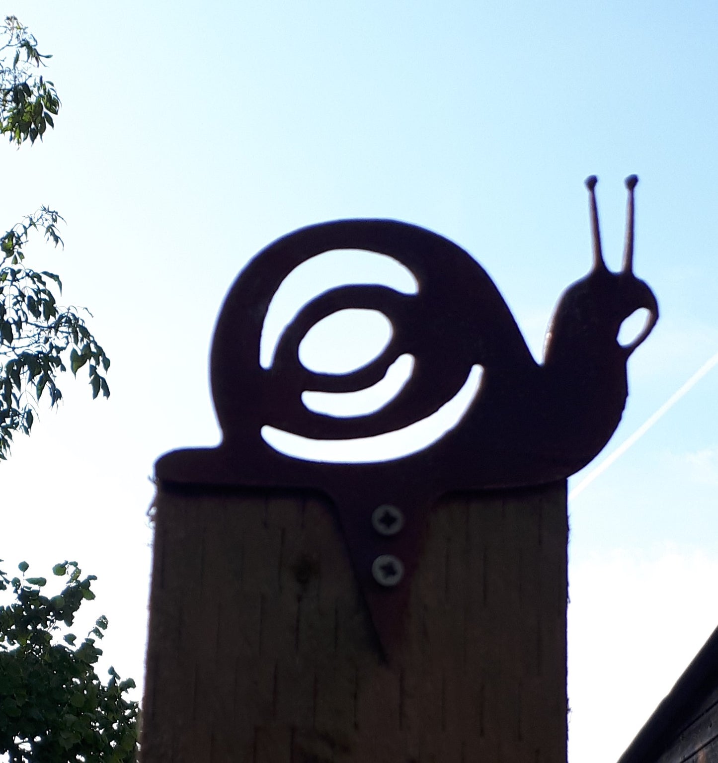 Rusty metal snail garden decoration fixed to a post against an early autumn sky, perfect garden art gift.