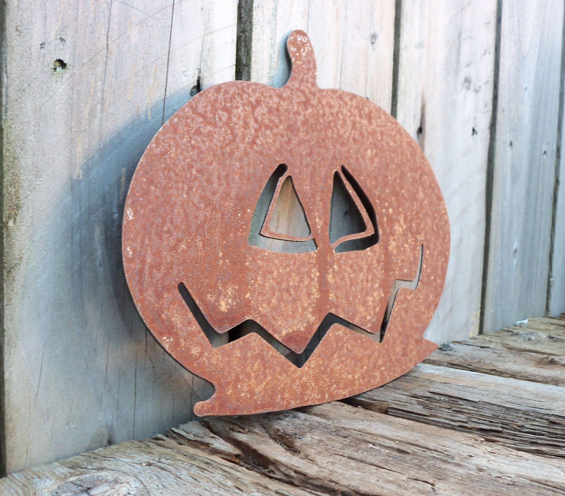 Rusted Metal pumpkin garden ornament on a wooden table, perfect Halloween gift.