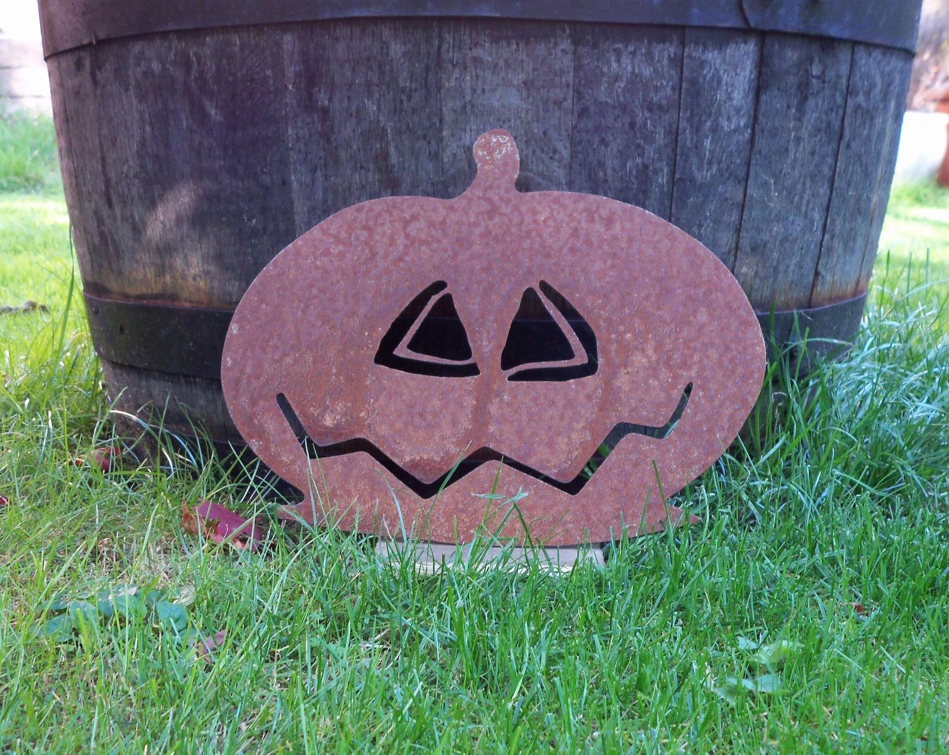 Rusty metal pumpkin garden ornament, rustic Halloween decor on grass, 225mm height x 300mm width, unique patina effect.