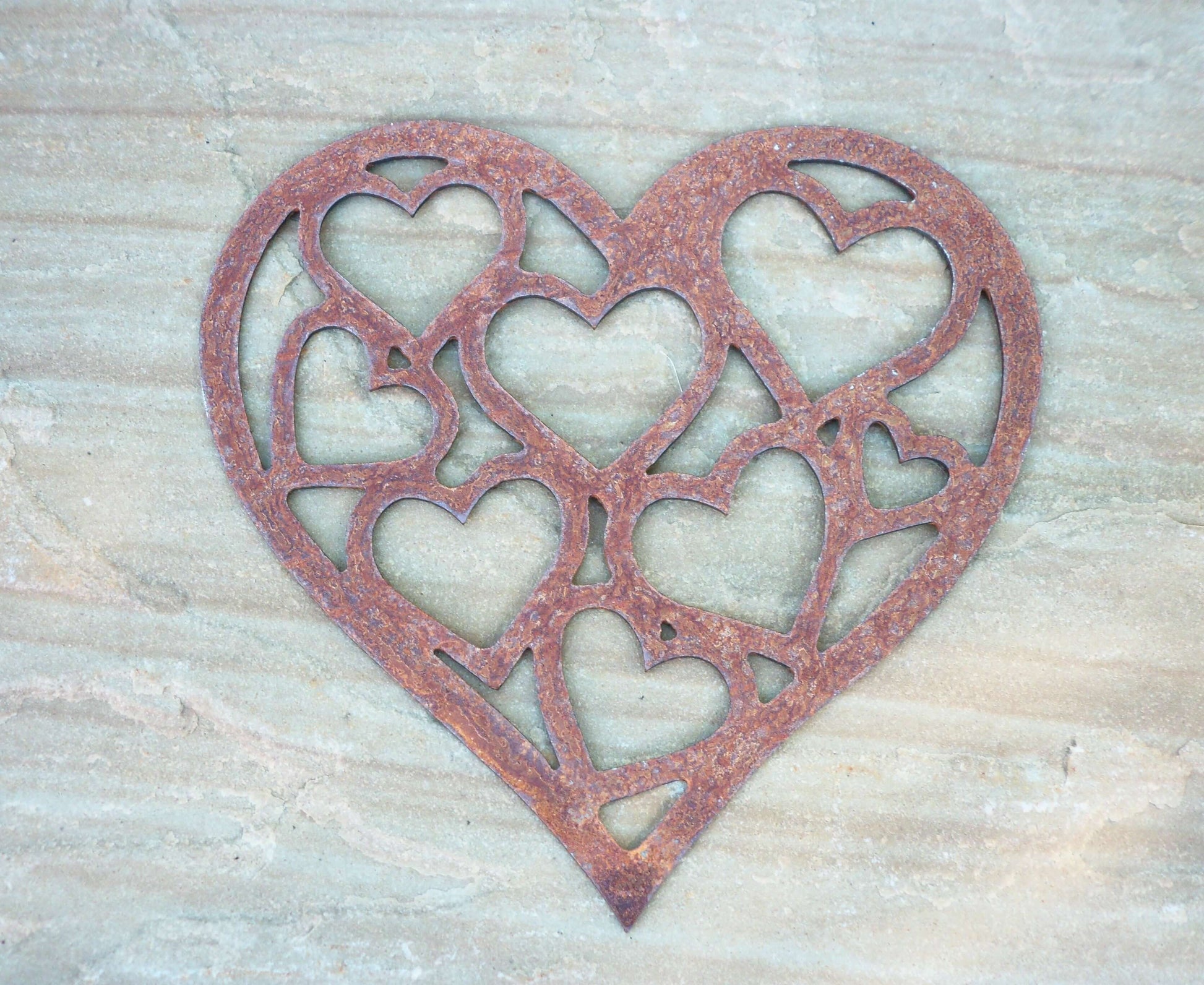 Rusty Metal LOVE HEART of HEARTS Garden Ornament on a stone surface, featuring intricate heart patterns.