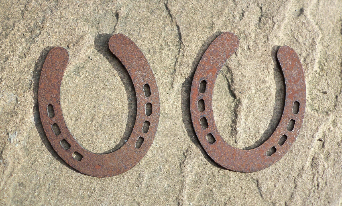 Rusty Steel PAIR OF HORSESHOES Garden Ornaments displayed on a stone surface, showcasing rustic metal art for outdoor decor.