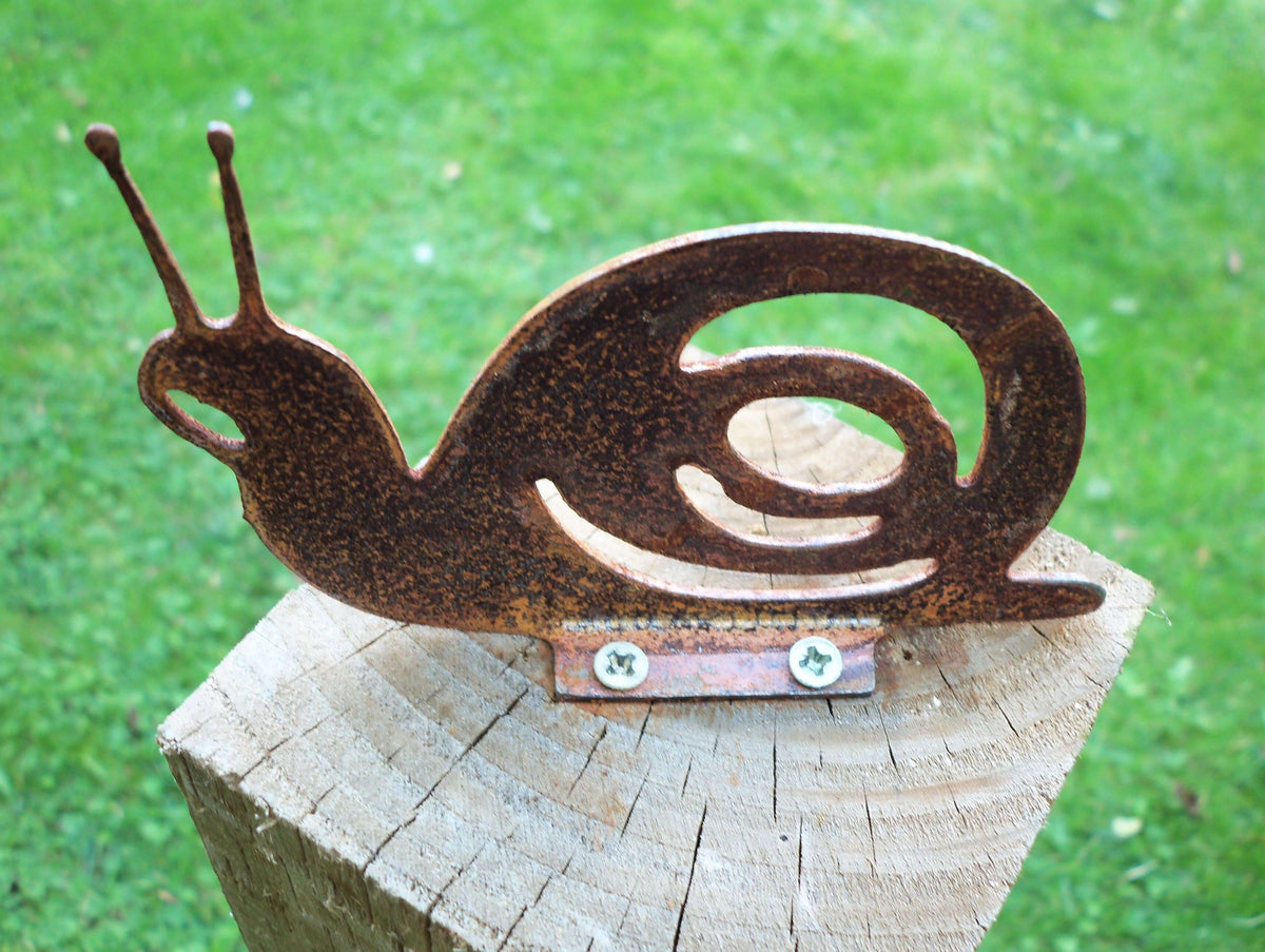 Rusty Steel Snail Garden Ornament perched on a wood post, showcasing its unique rustic design and charm.