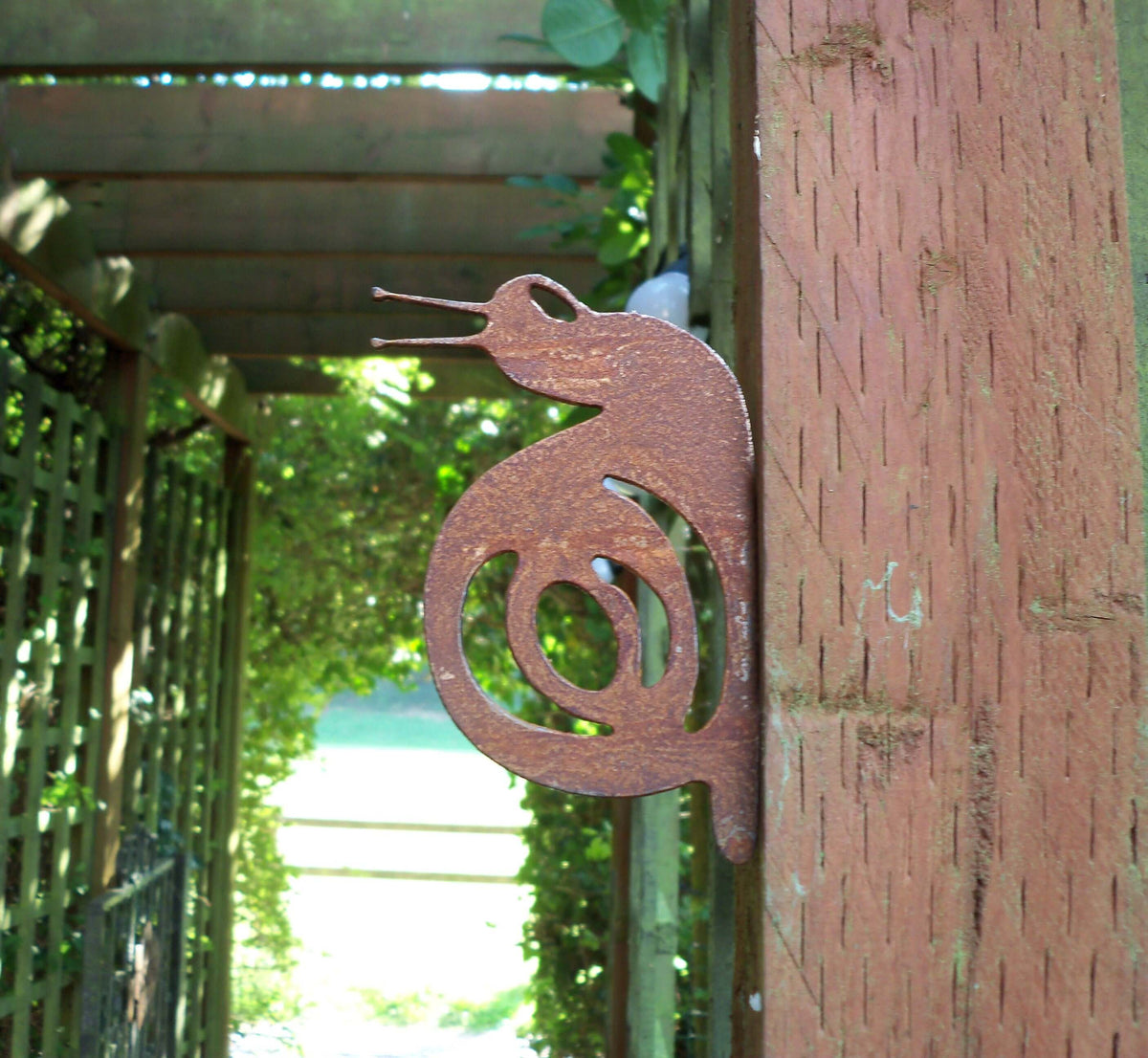 Rusty Steel Snail Garden Ornament attached to a fence post, adding rustic charm to the garden.