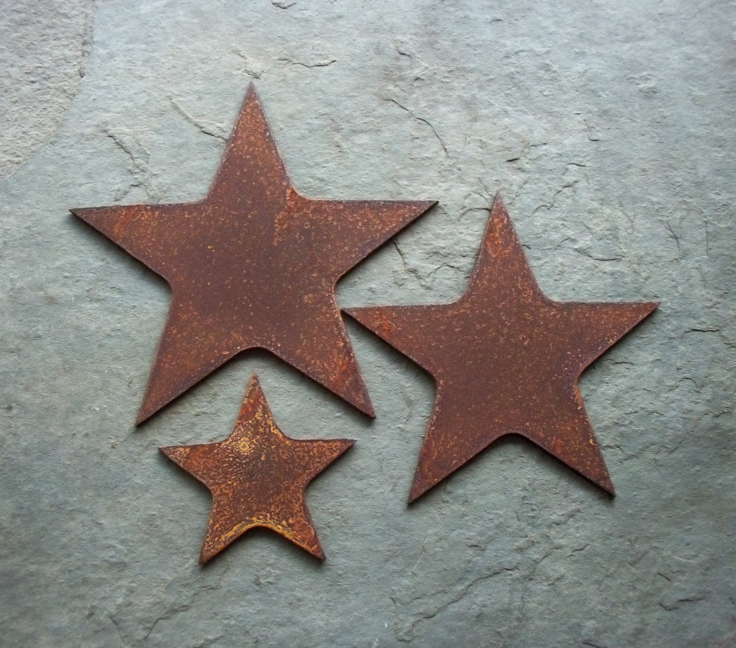 Rusted metal stars set of three garden ornaments, rusty steel garden art, shown on a grey backdrop.