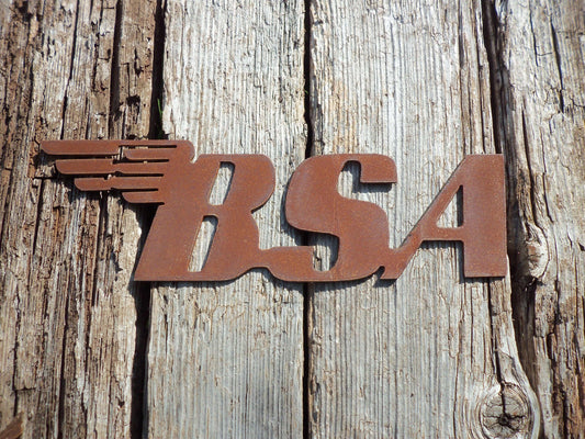 Rustic Metal BSA Motorcycle Badge Sign garden ornament on a wooden backdrop, classic old motorbike rusted steel art.