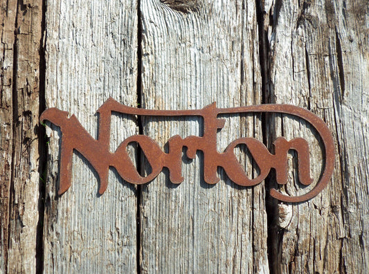 Rustic metal Norton Motorcycle badge sign garden ornament on a wooden background, classic old style rusted steel motorbike sign.