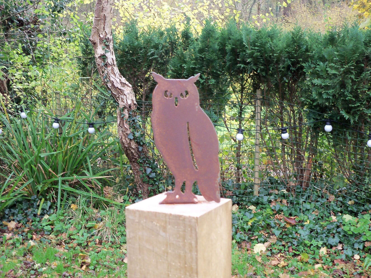 Rusted Steel Owl Garden Ornament on a wooden post in a garden with greenery and fairy lights.