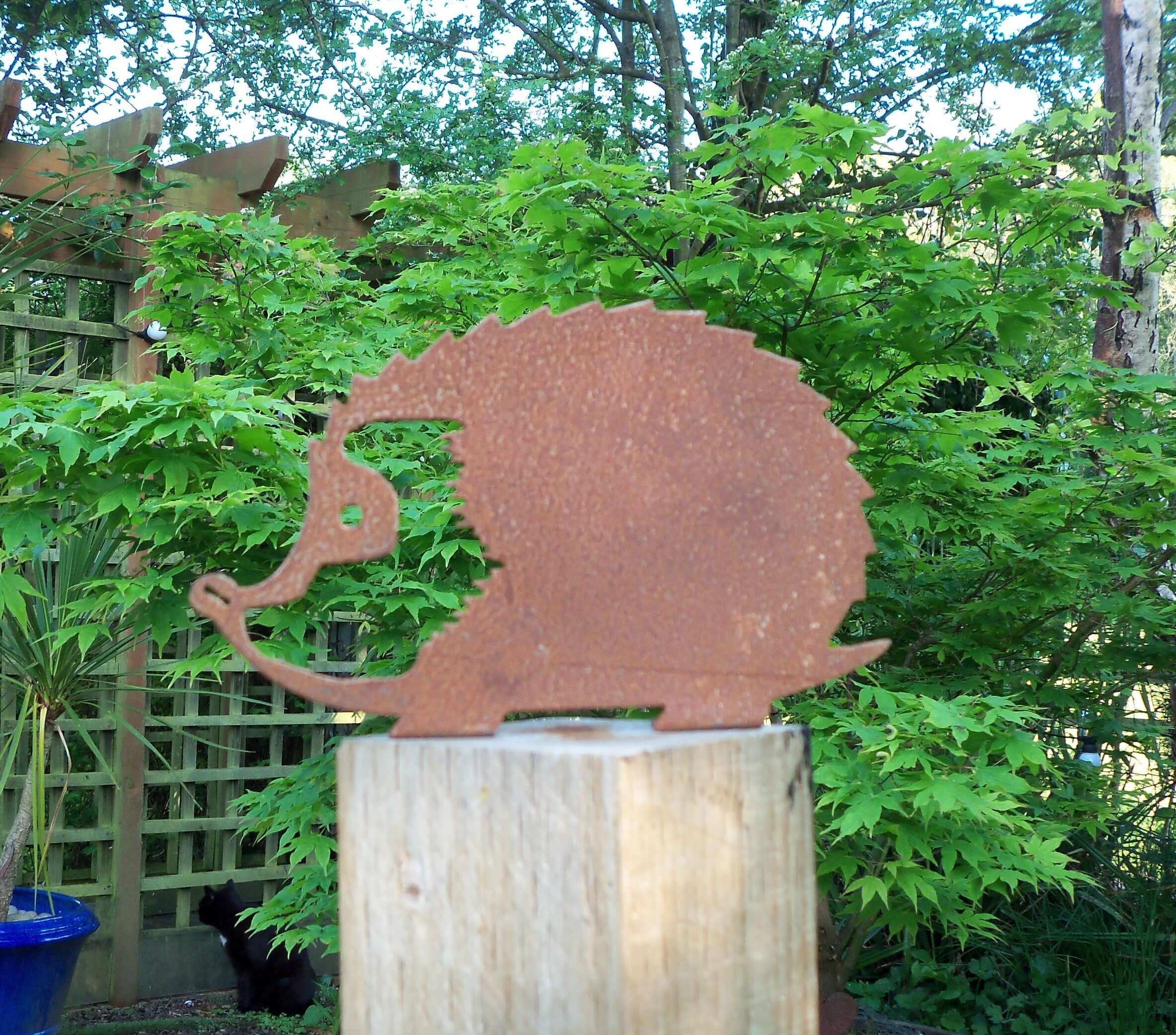 Rusty Metal HEDGEHOG Garden Ornament displayed on a wooden post in a lush garden setting.
