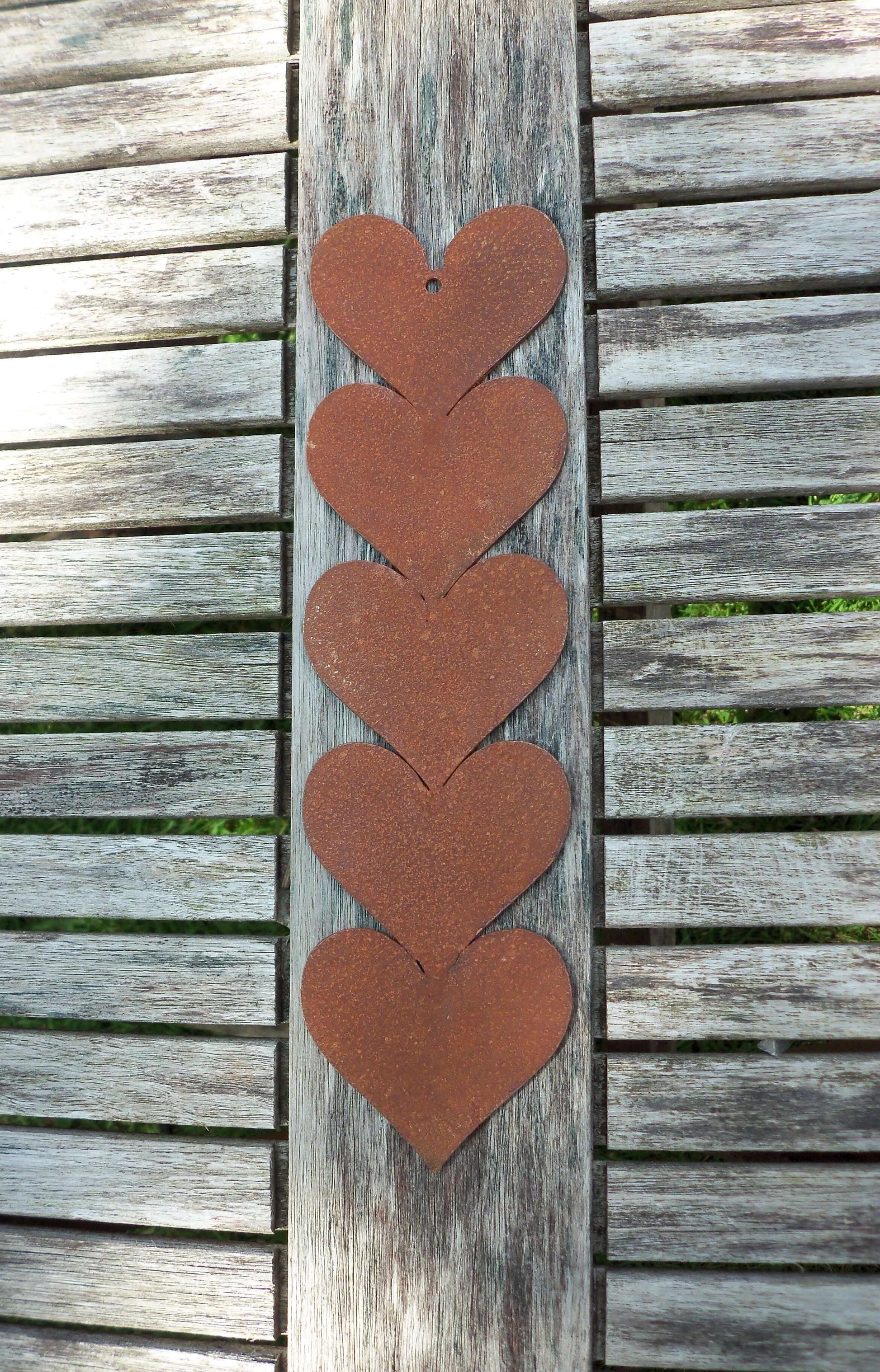 Rusty metal hanging hearts garden ornament displayed on a wooden table, featuring five joined hearts.