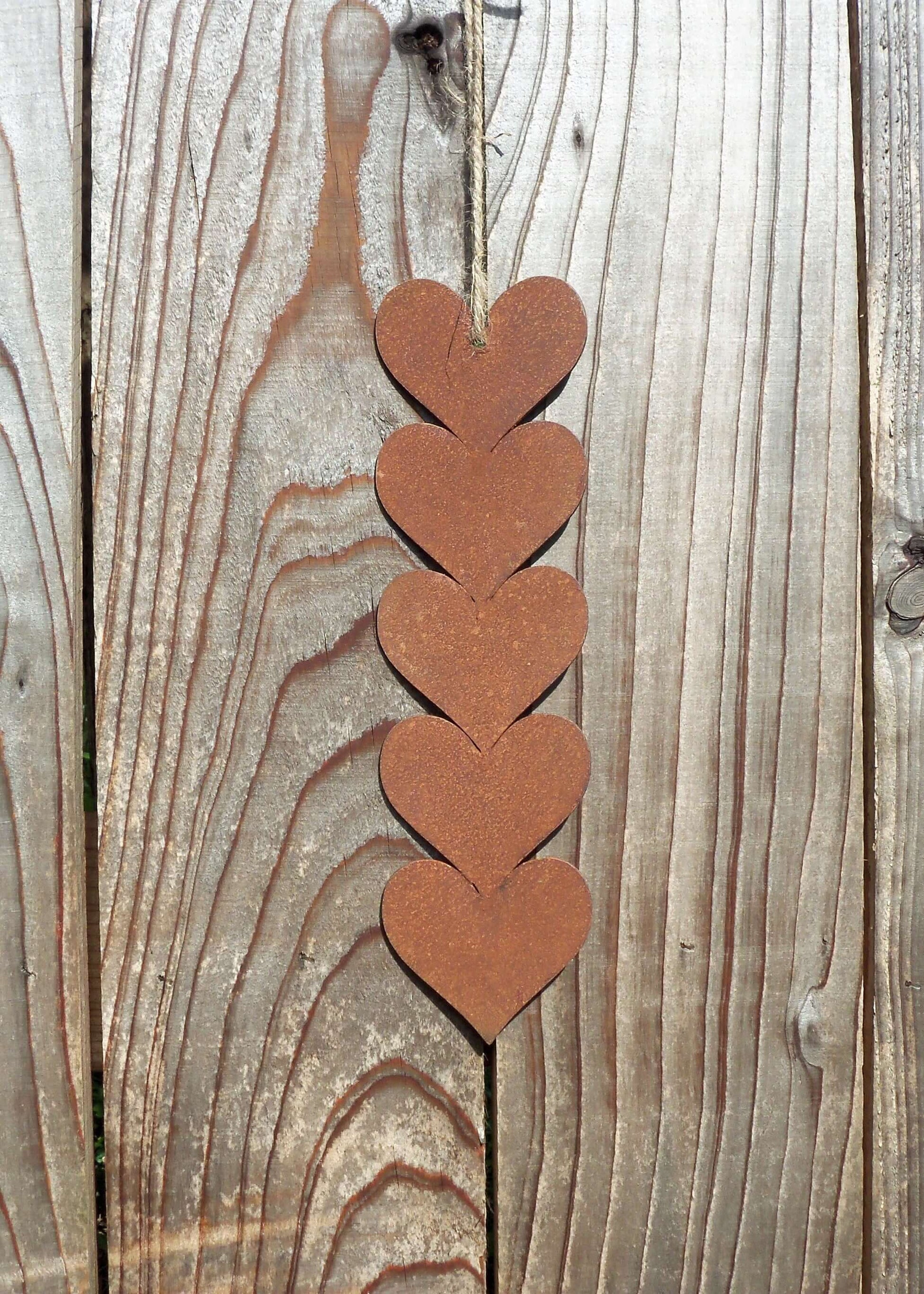 Rusty metal hanging hearts garden ornament displayed against wooden background.