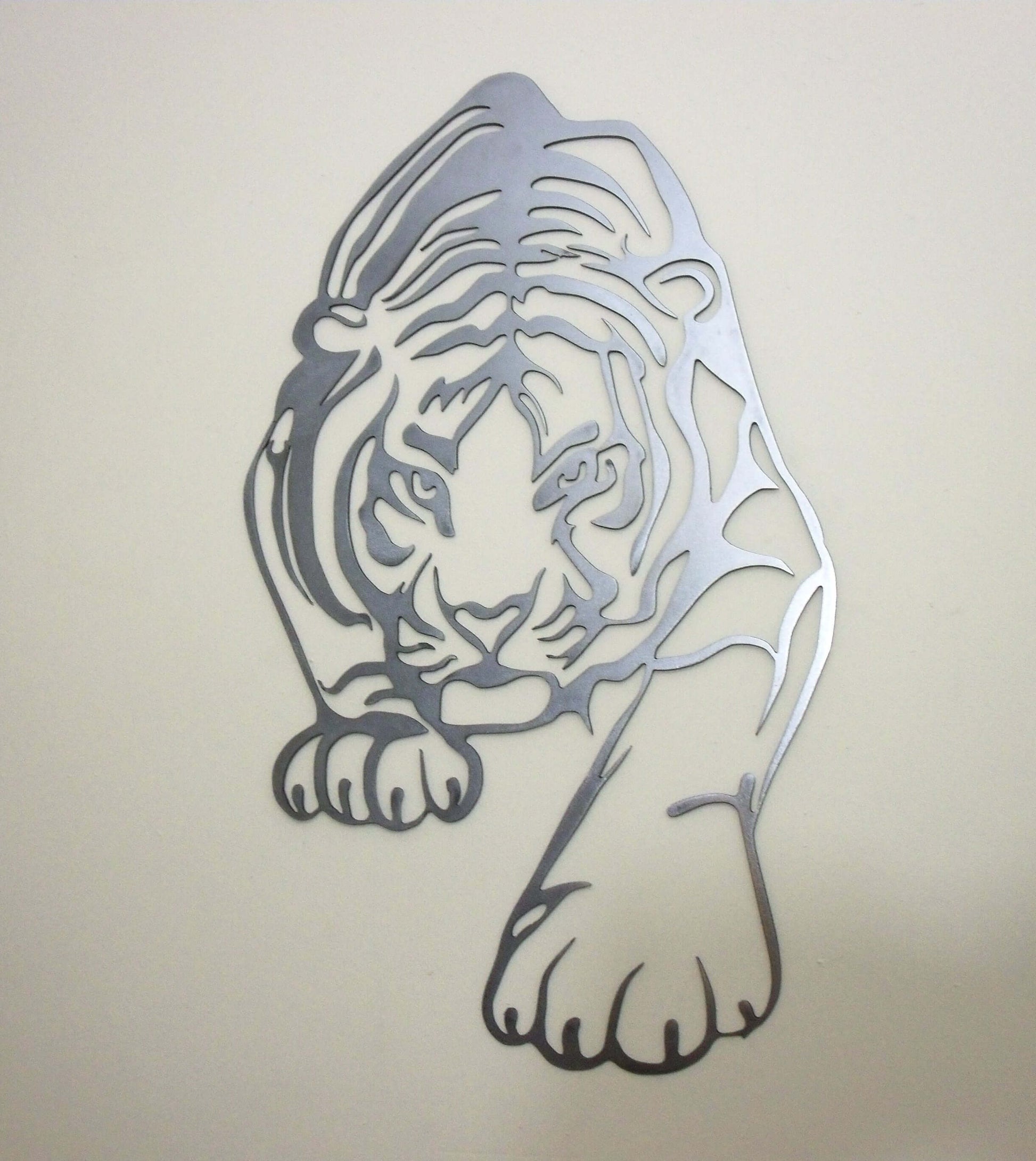Metal tiger wall art mounted on a beige wall in a modern living space