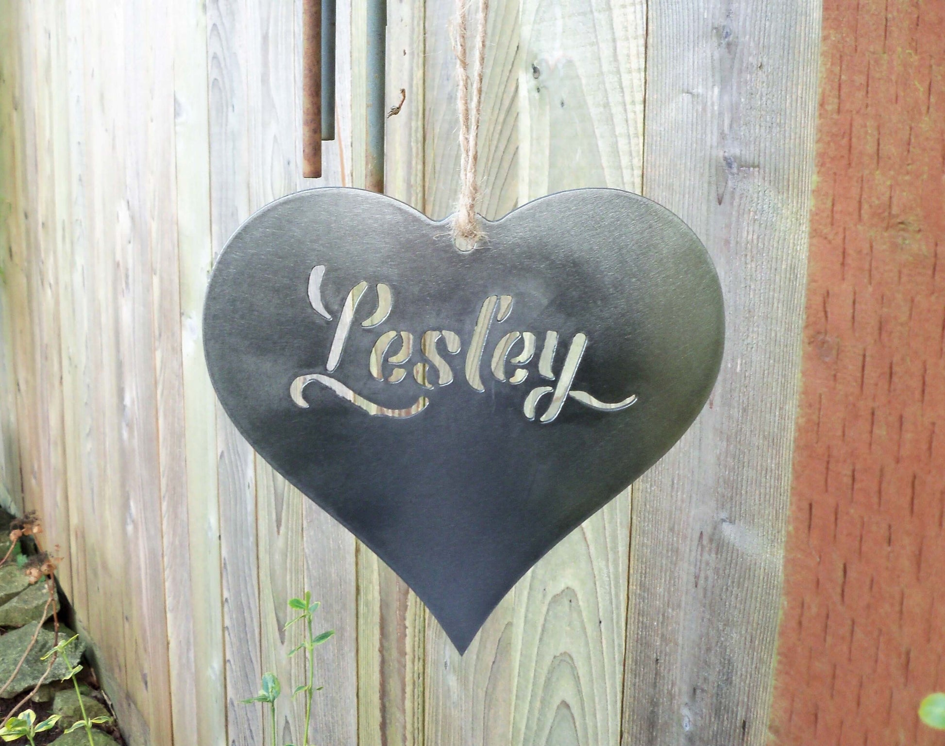 Personalised metal hanging heart garden ornament with the name 'Lesley' cut out, rustic outdoor decor
