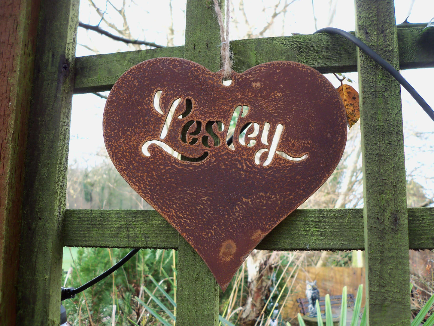 Personalised rusty metal hanging heart ornament plaque displayed on pergola