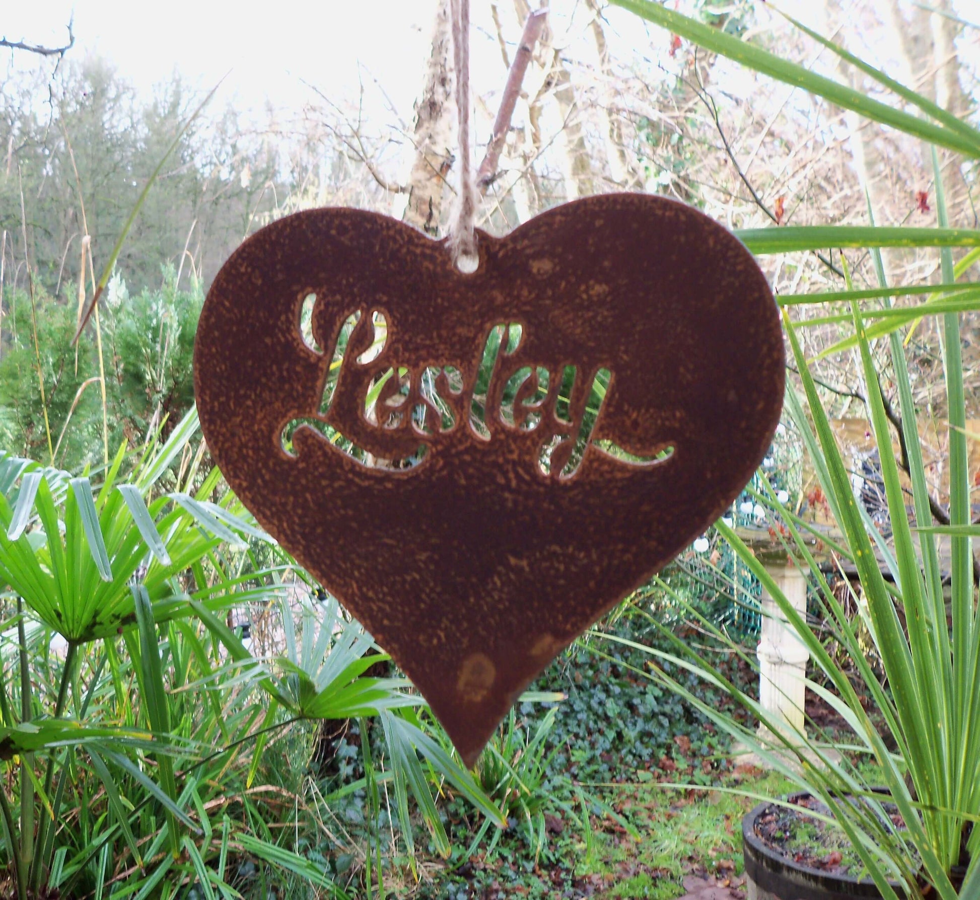 Personalised rusty metal hanging heart ornament displayed in garden setting