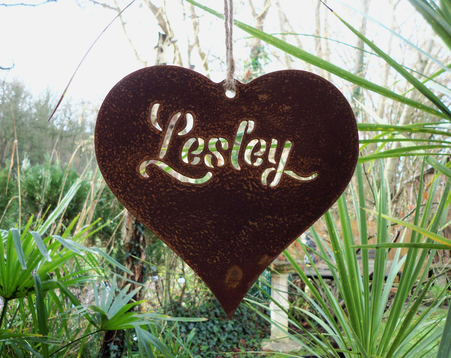 Personalised rusty metal hanging heart ornament displayed in garden