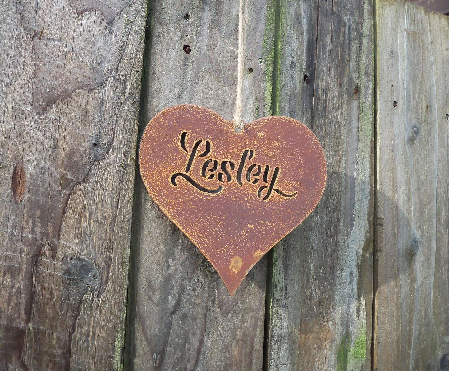 Weathered Personalised rusty metal hanging heart ornament hanging on a fence