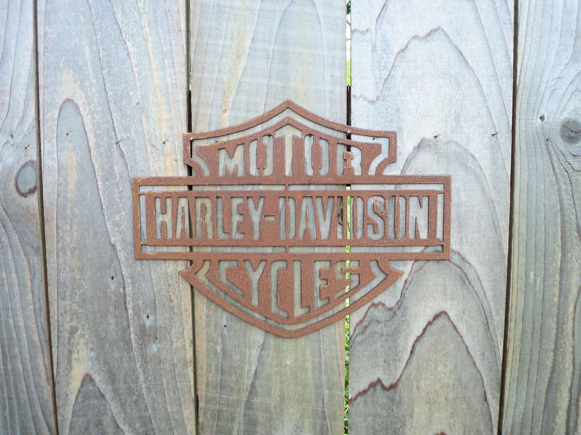 Rustic Metal Harley Davidson Motorcycle Badge Sign on a grey wooden fence
