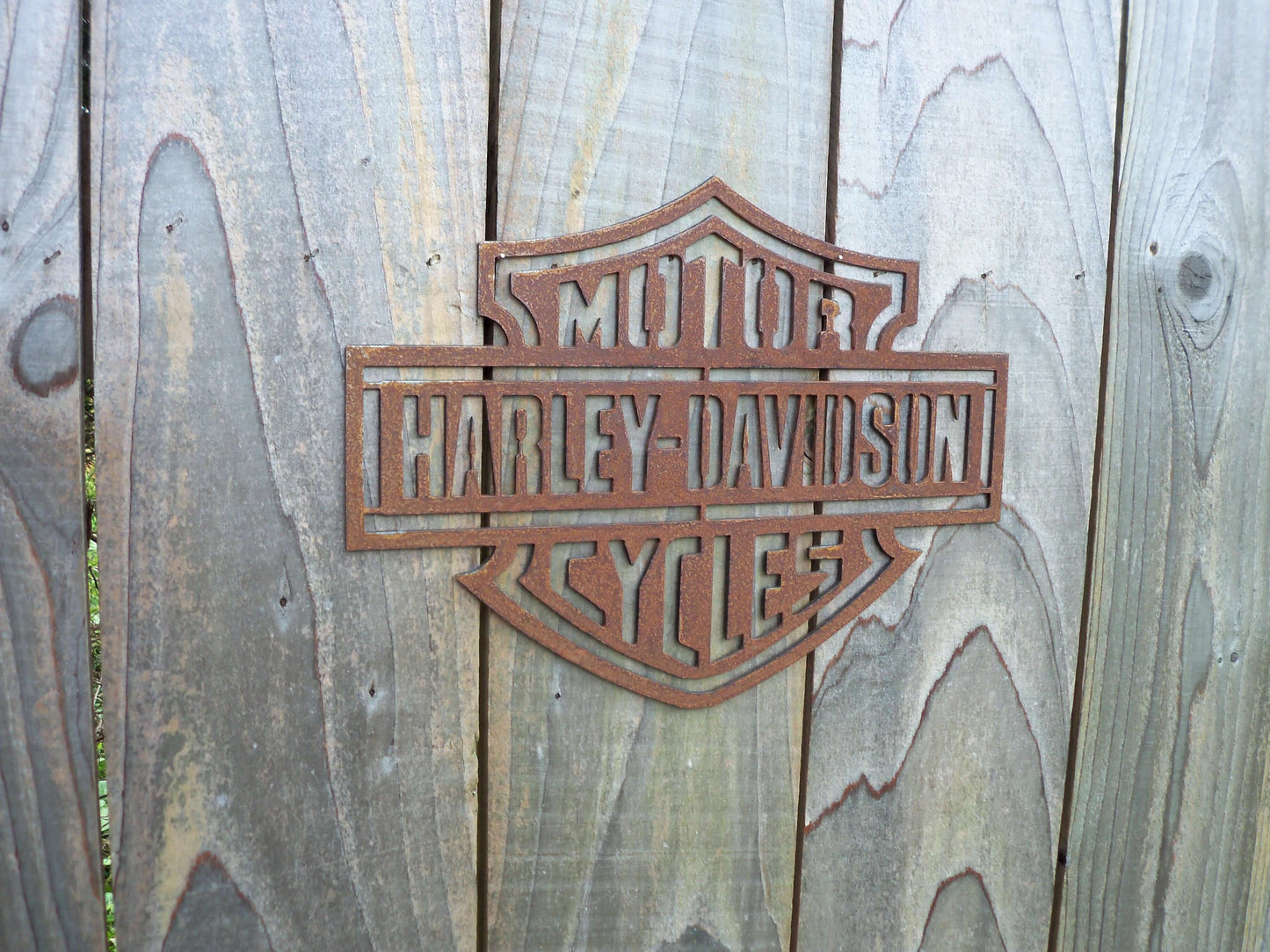Rustic Metal Harley Davidson Motorcycle Badge Sign on a wooden garden fence 