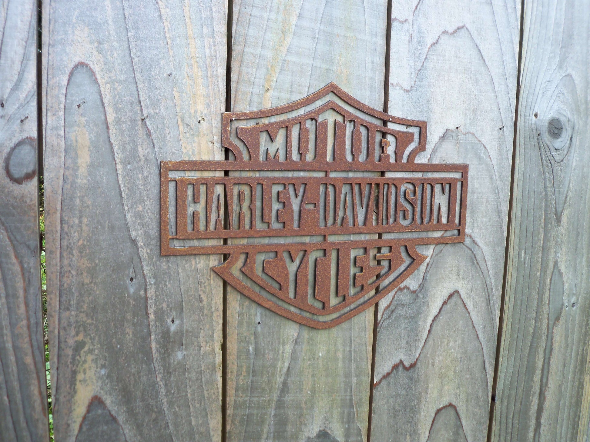 Rustic Metal Harley Davidson Motorcycle Badge Sign on a wooden garden fence 