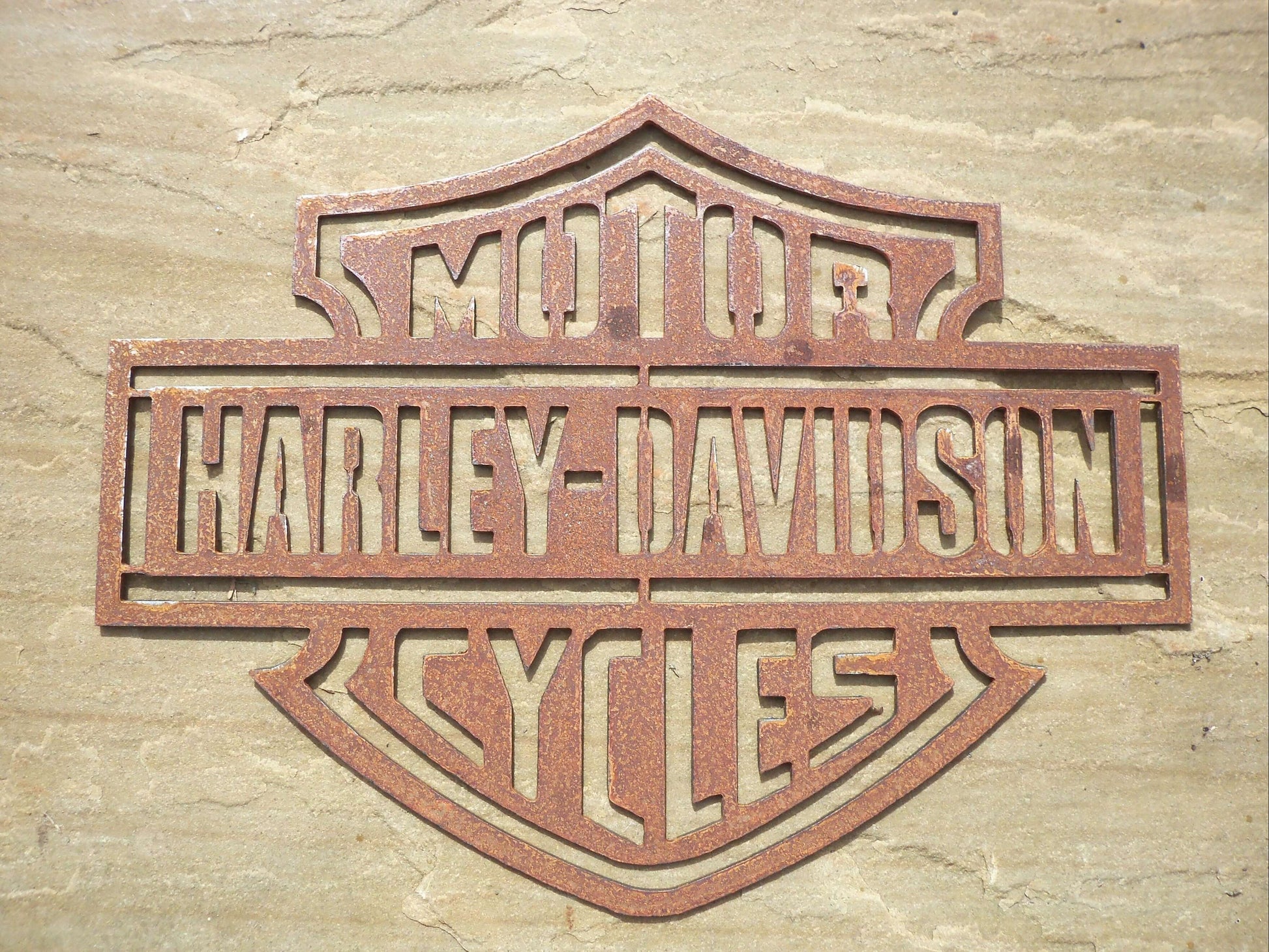 Rustic Metal Harley Davidson Motorcycle Badge Sign on a stone background