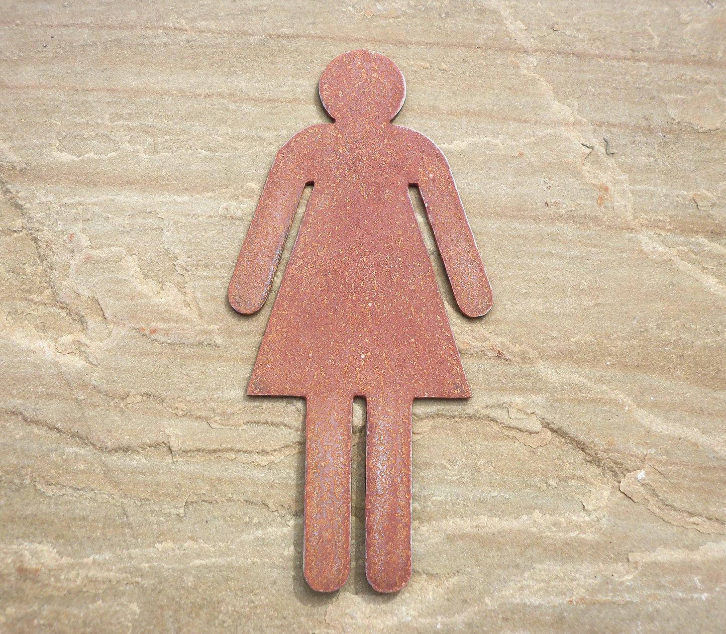 Rustic Metal WC Toilet Door Signs - female symbol on a stone surface