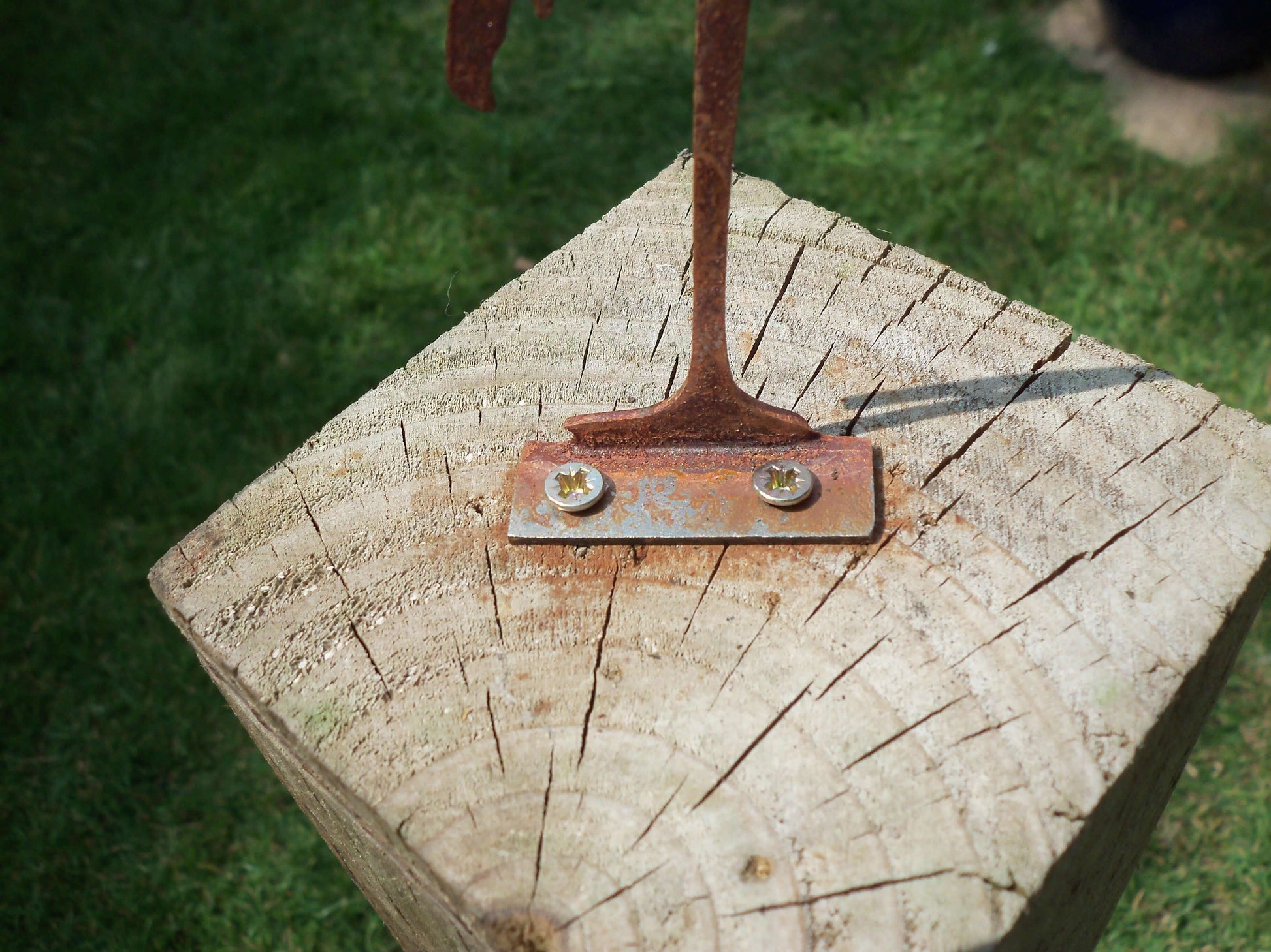 Rusty Metal Flamingo garden ornament secured on a rustic wooden fence post with screws.