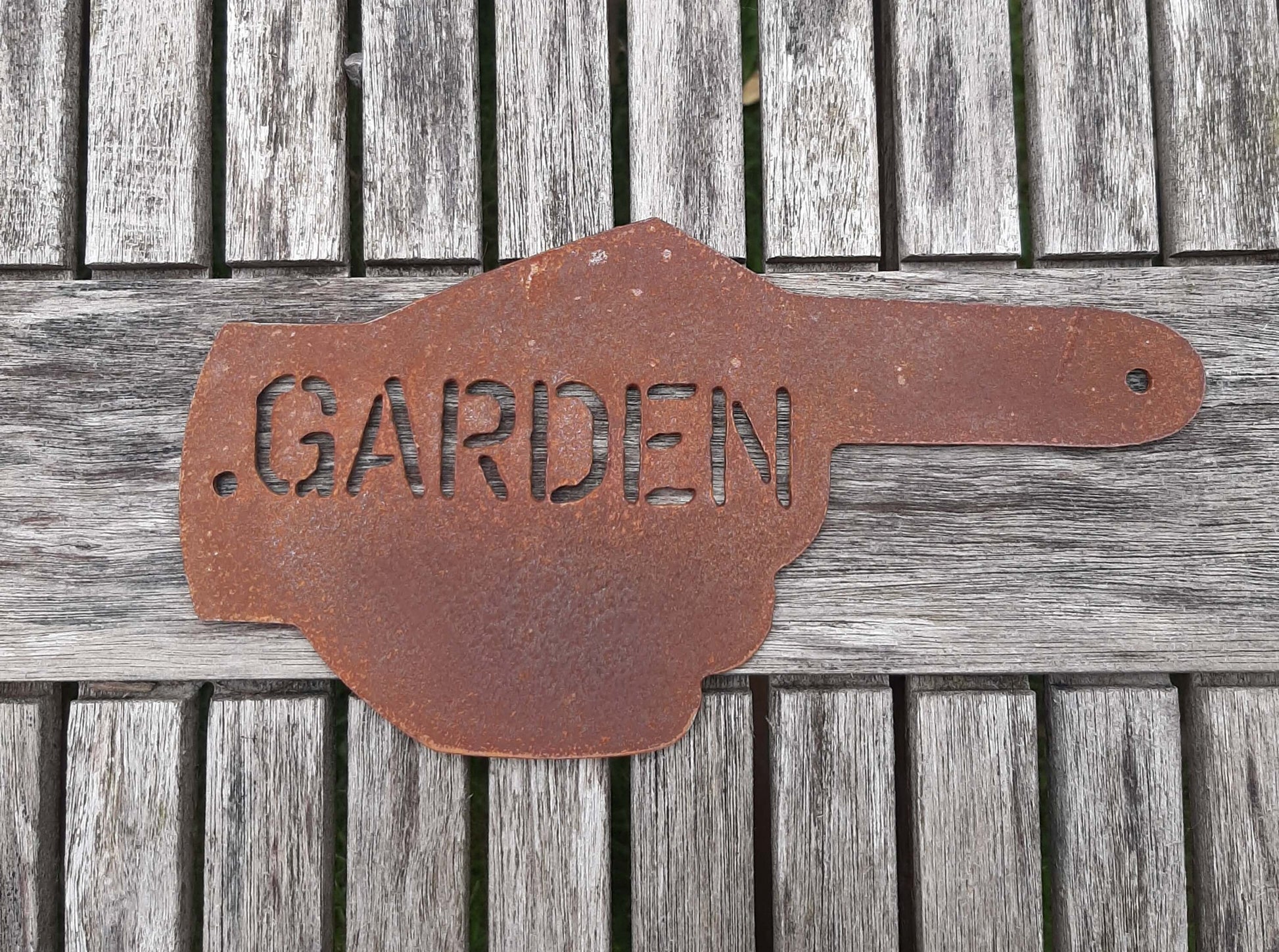 Rusty Metal Hand Pointer Arrow Garden Sign Ornament displayed on a wooden surface pointing towards a garden.