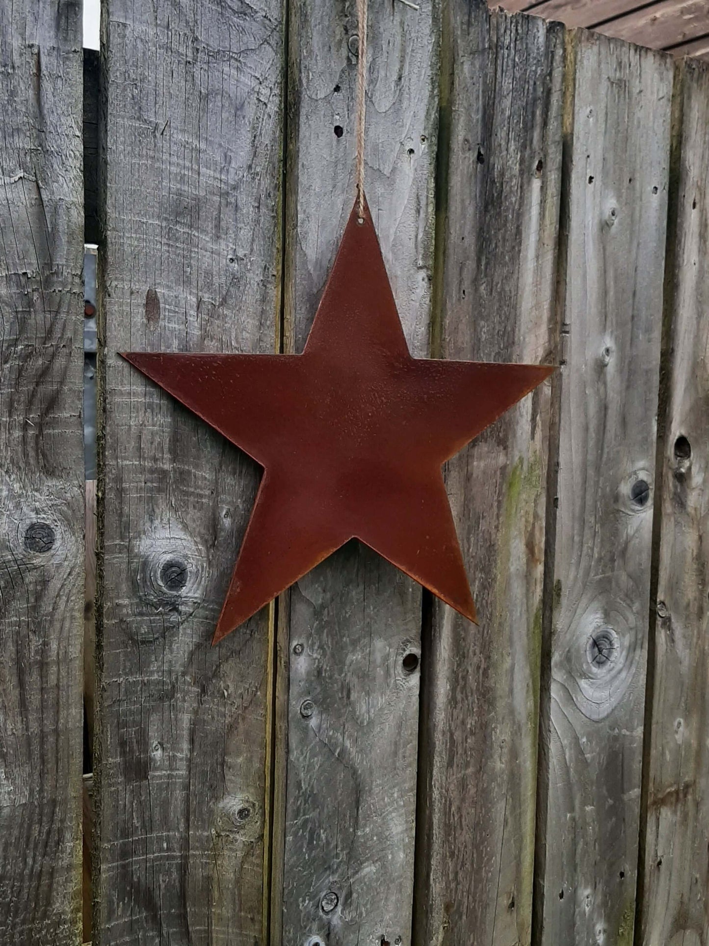 Rusty Metal STAR Garden Ornament on a wooden garden fence
