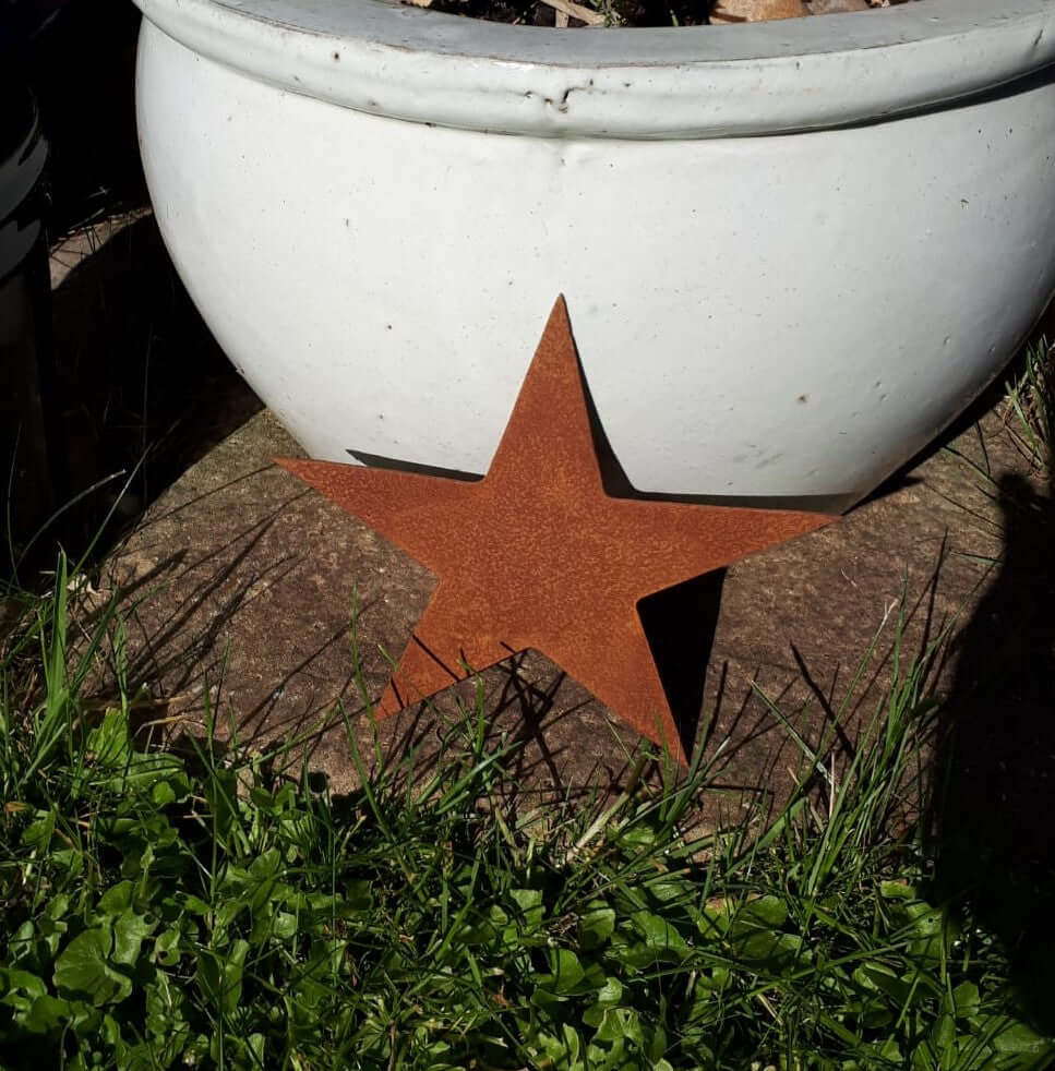 Rustic Steel Star Garden Gift Set - Rusted medium metal star garden ornament standing against a white planter on the path