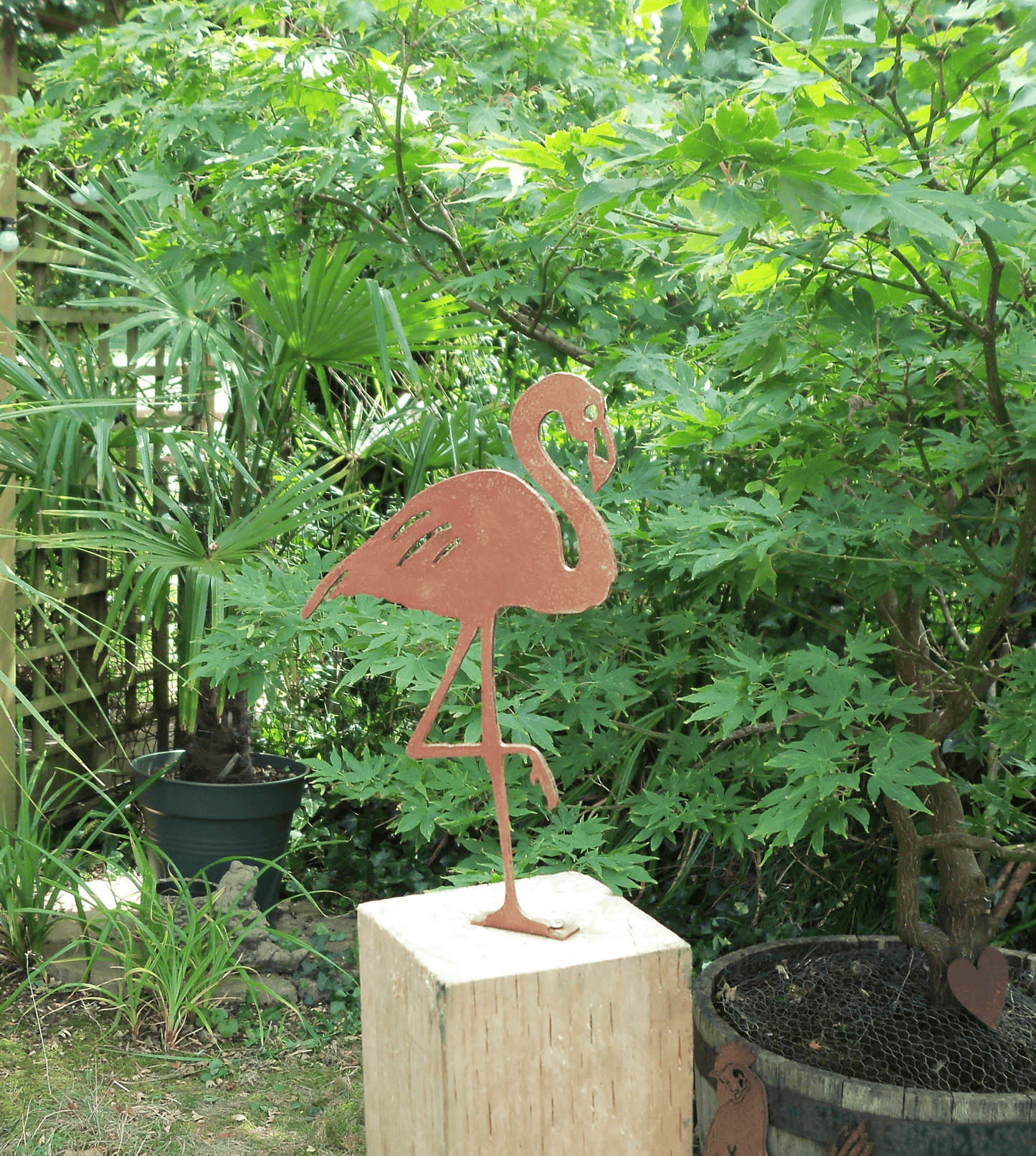Rusty Metal Flamingo Garden Ornament displayed in a lush garden setting, featuring rustic design and steel construction.