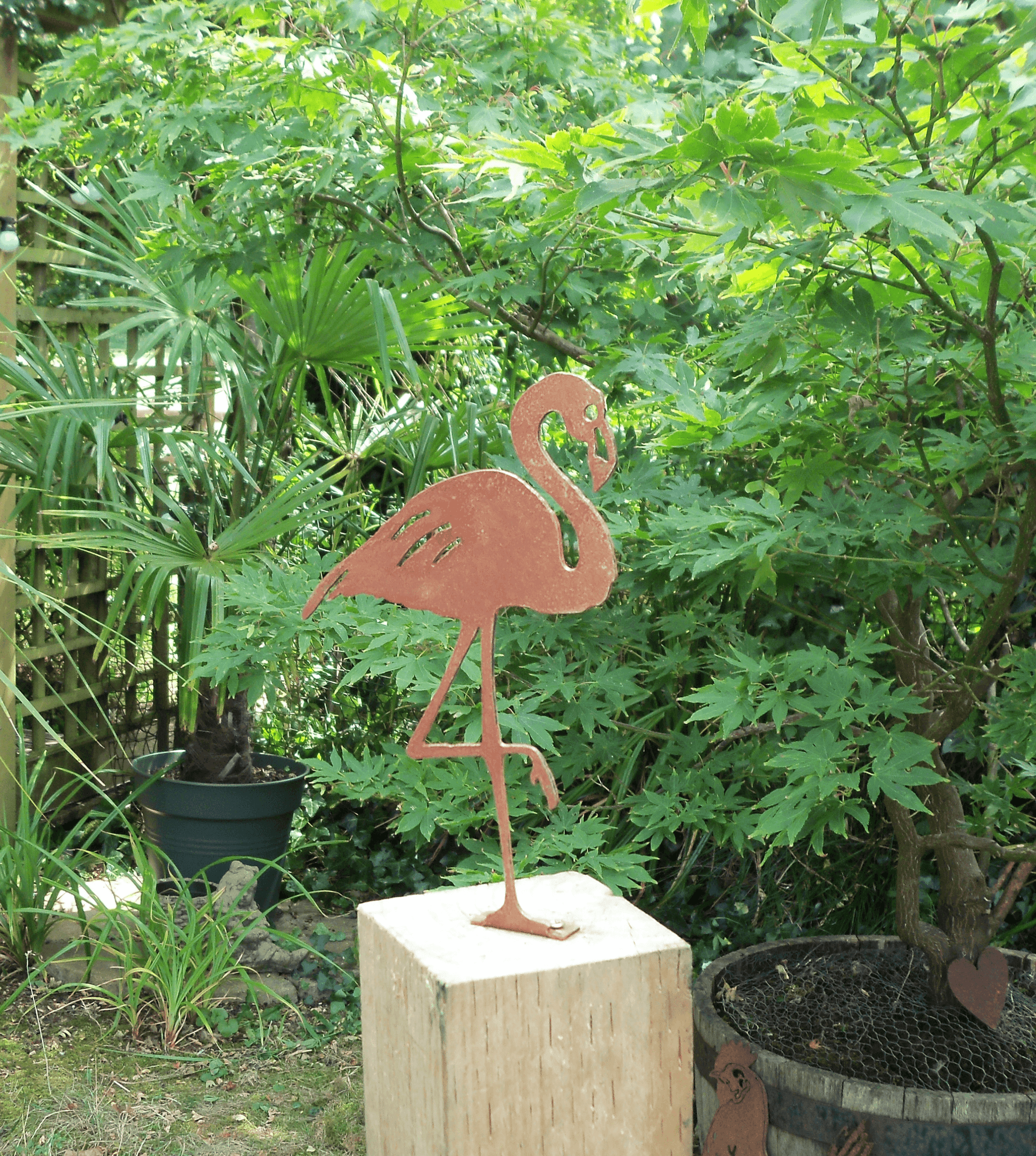 Rusty Metal Flamingo Garden Ornament displayed in a lush garden setting, featuring rustic design and steel construction.