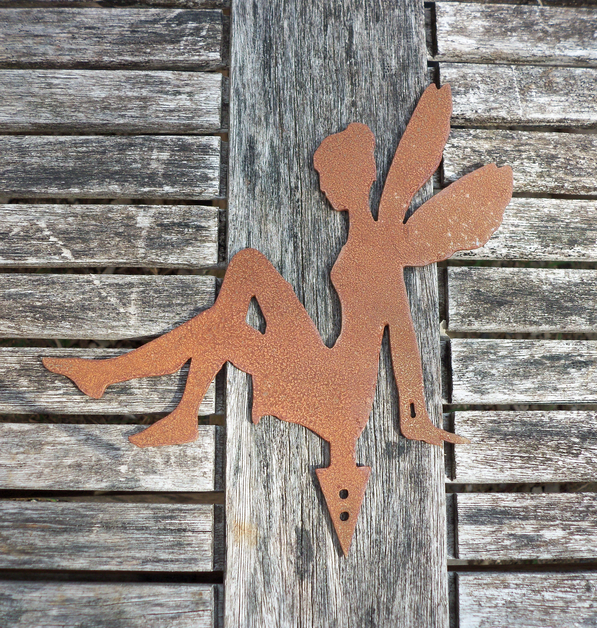 A rusty steel fairy garden ornament showing it's ground pot spike on a wooden background.