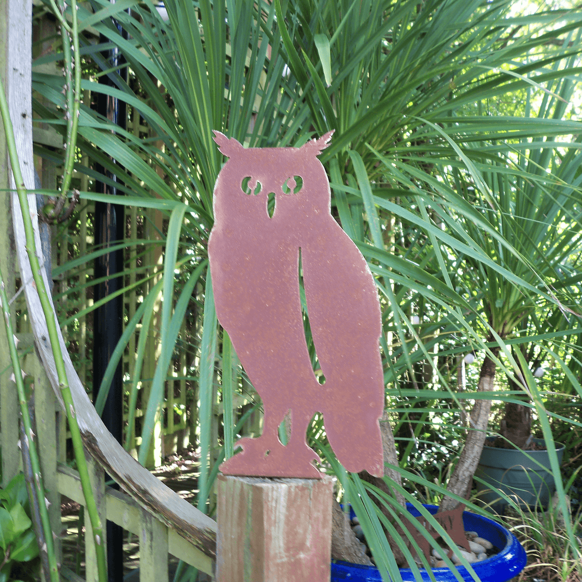 Rustic Steel OWL Garden Ornament standing on a fence post among greenery in a garden setting.