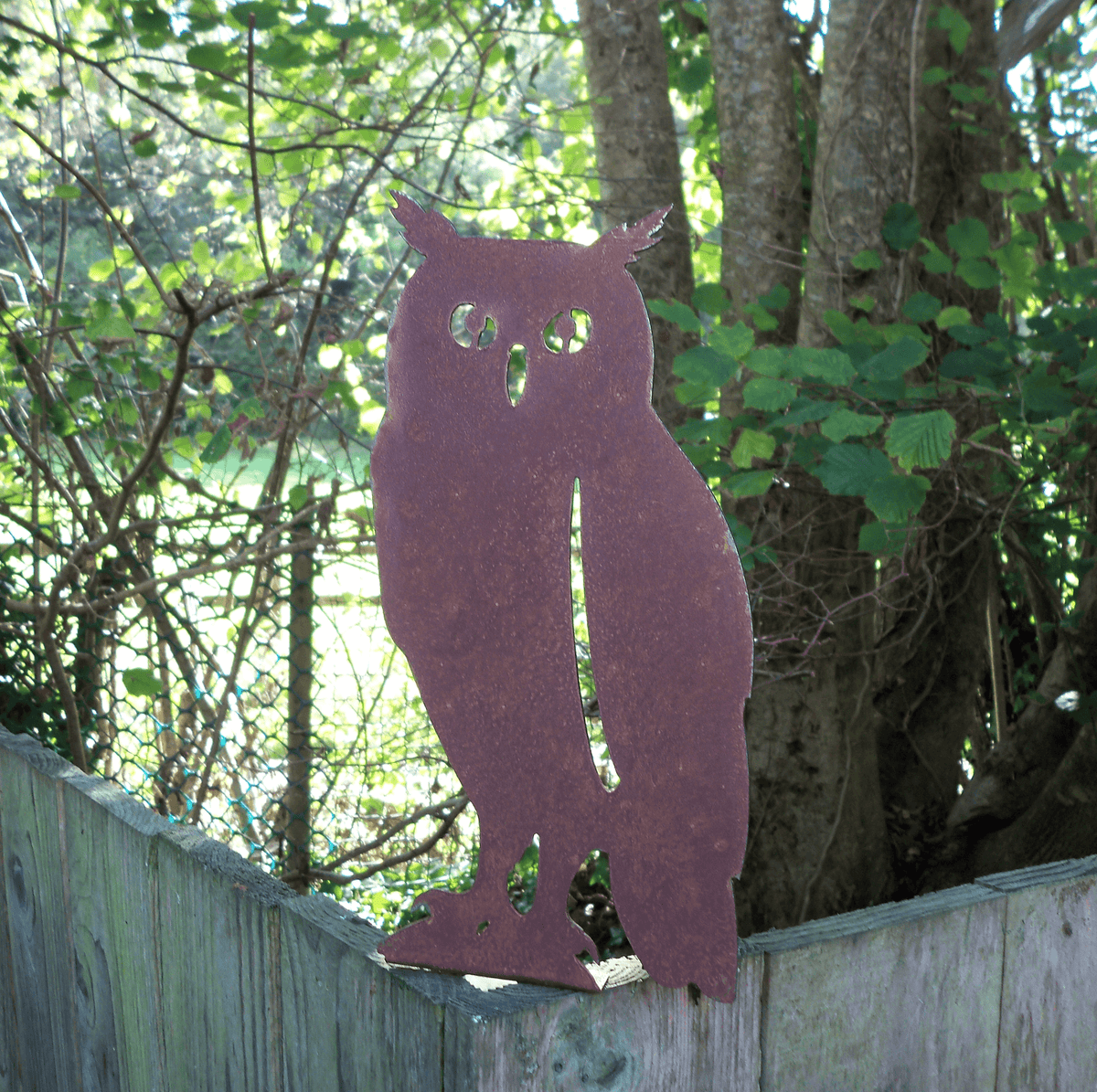 Rustic Steel OWL Garden Ornament standing on a fence post, showcasing its unique rusted finish and rustic charm.