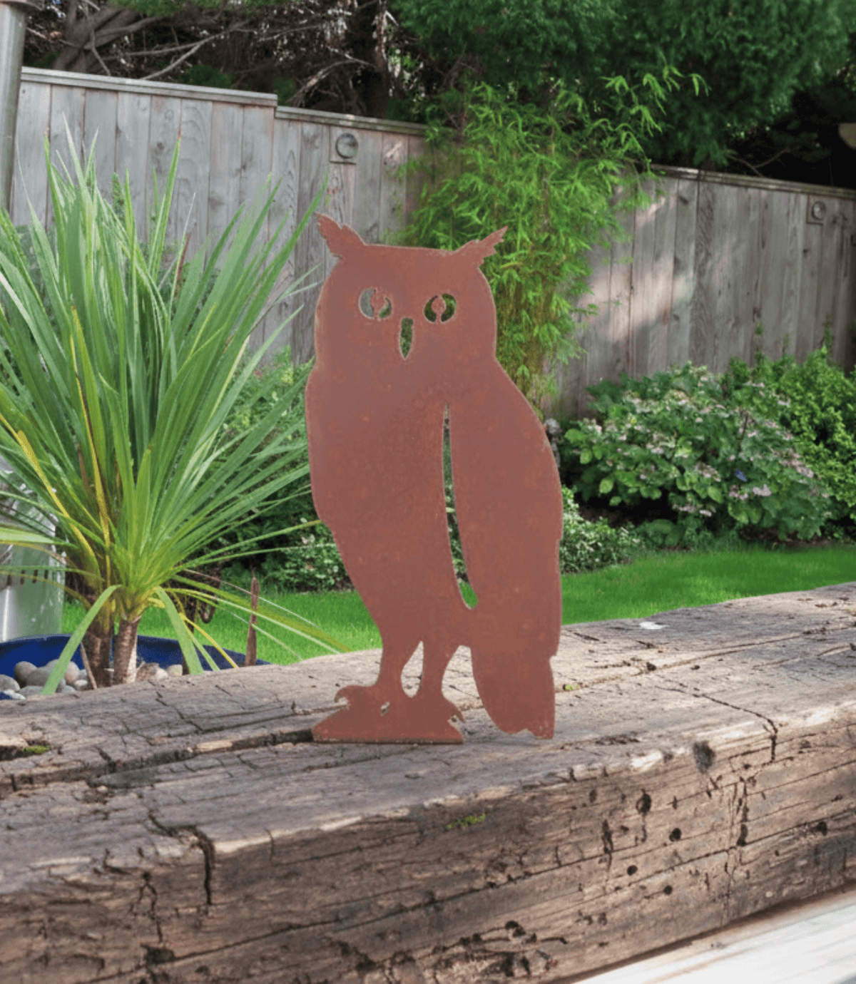Rustic Steel OWL Garden Ornament displayed in a garden setting, showcasing unique rusted finish and standing on a wooden log.