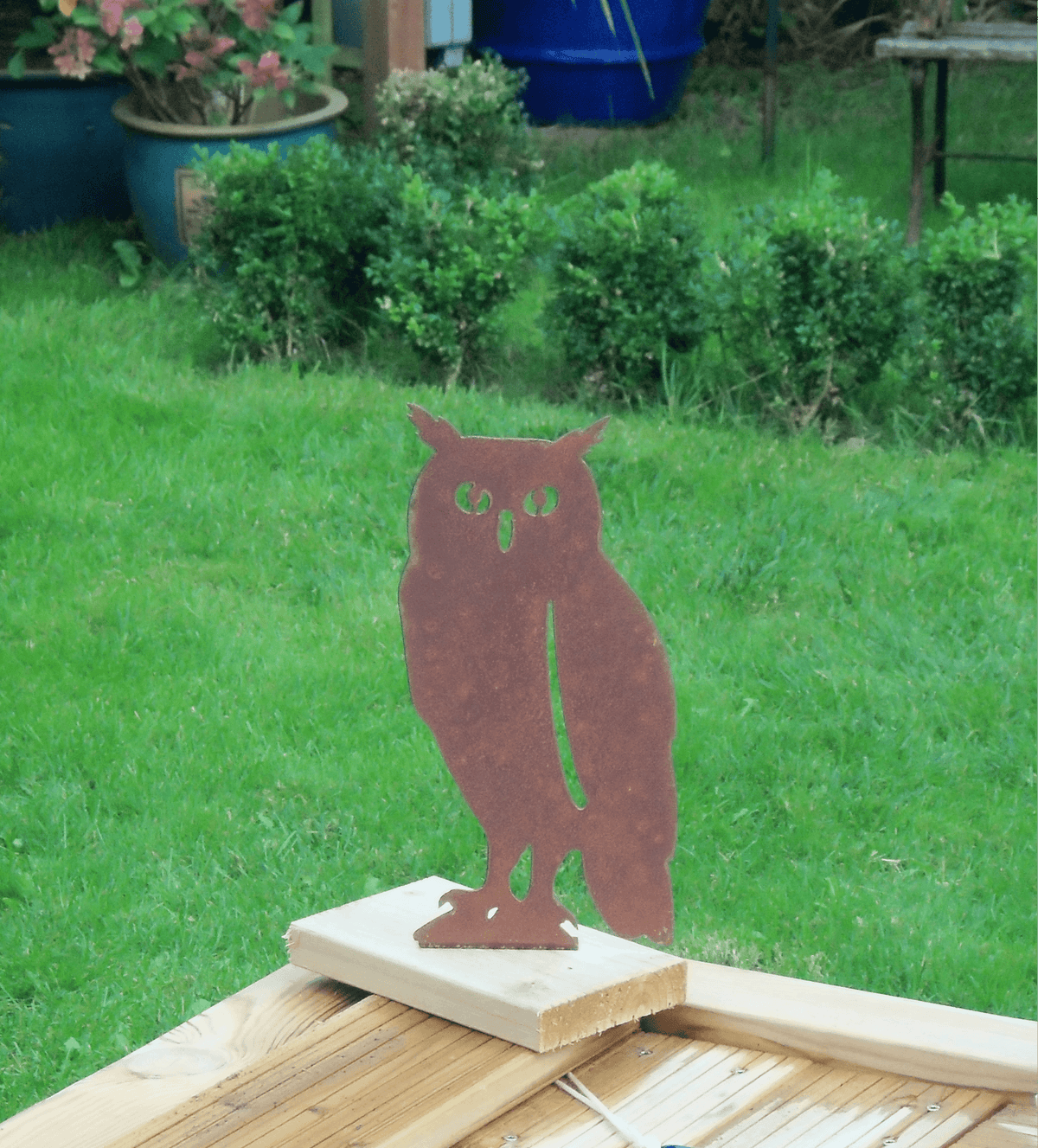 Rustic Steel OWL Garden Ornament displayed on wooden base in green garden setting.