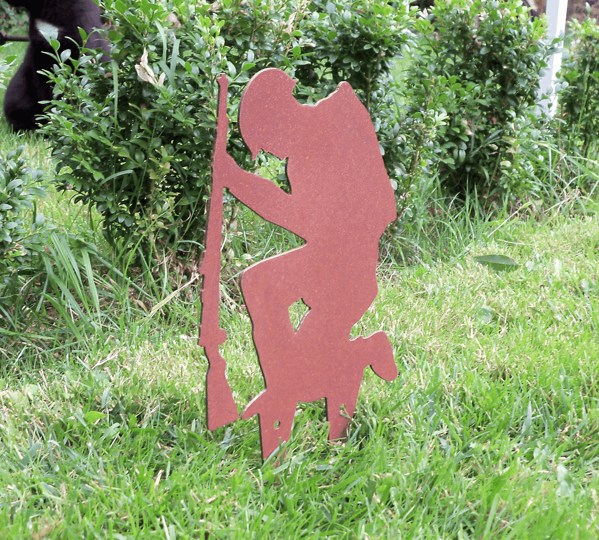 Rustic Steel SOLDIER Garden Ornament displayed in grass, featuring a kneeling soldier silhouette with a rifle.