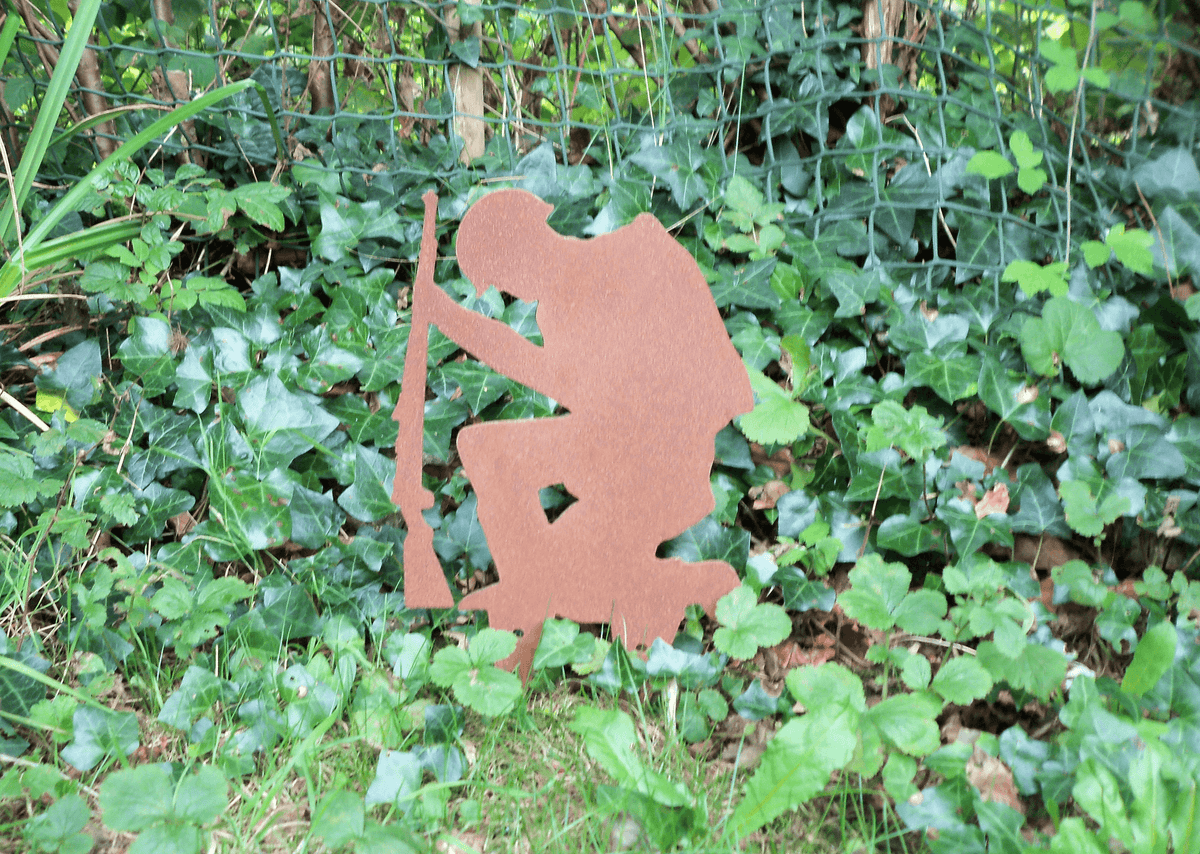 Rustic Steel SOLDIER Garden Ornament in a lush garden setting, showcasing a kneeling soldier silhouette with a rifle.
