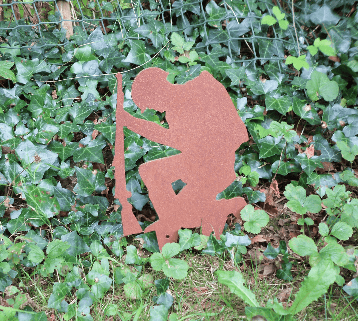 Rustic Steel SOLDIER Garden Ornament displayed among greenery as a unique metal military art decoration.