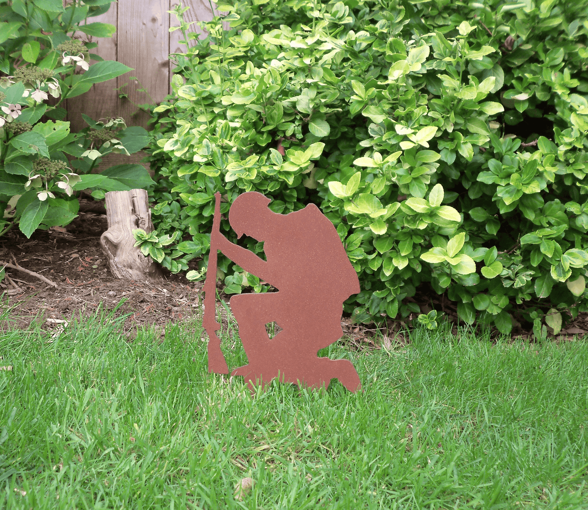 Rustic Steel SOLDIER Garden Ornament displayed in a garden, featuring a kneeling soldier silhouette with a rifle.