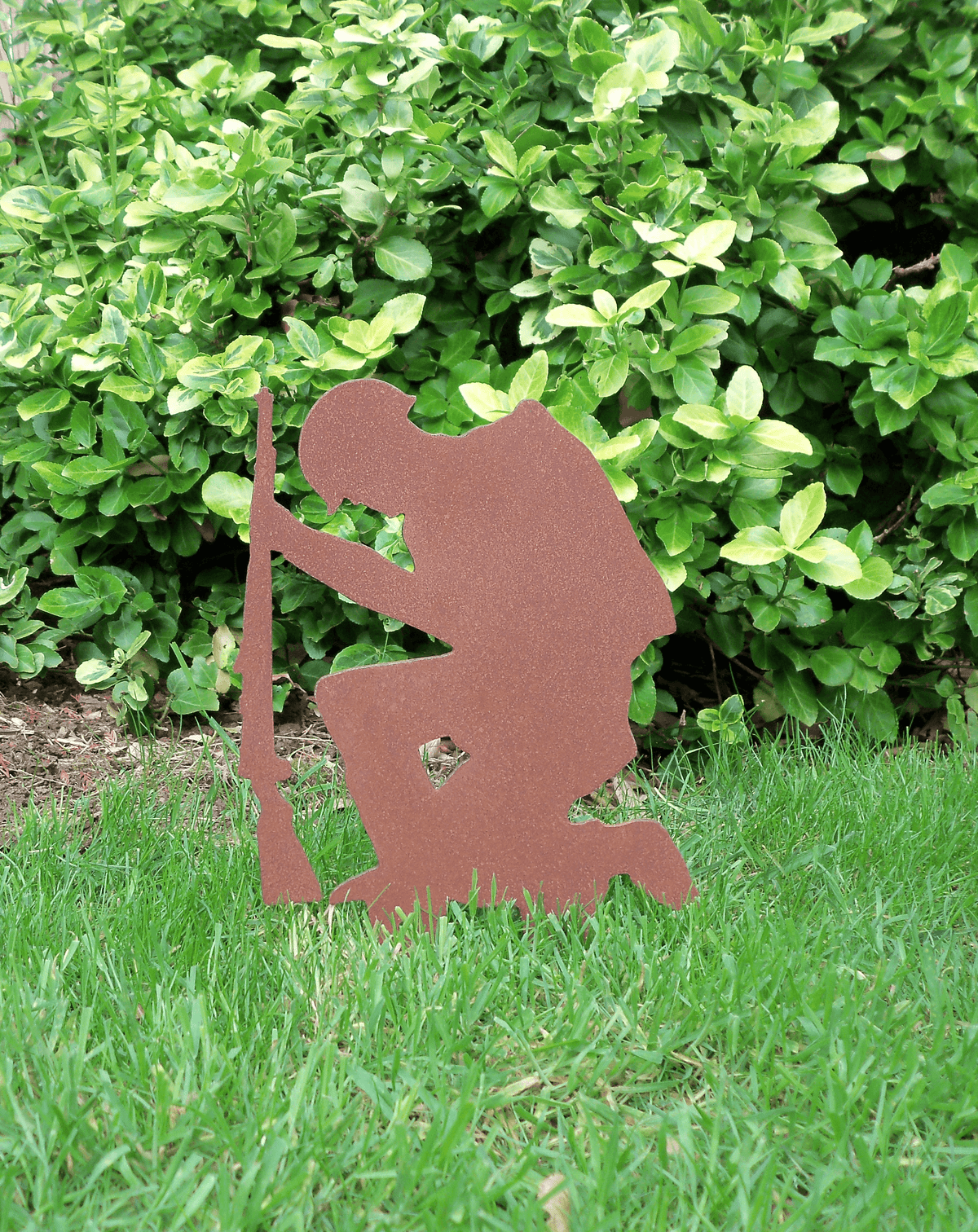 Rustic Steel SOLDIER Garden Ornament - Kneeling Metal Military Art Decoration in garden with green foliage.