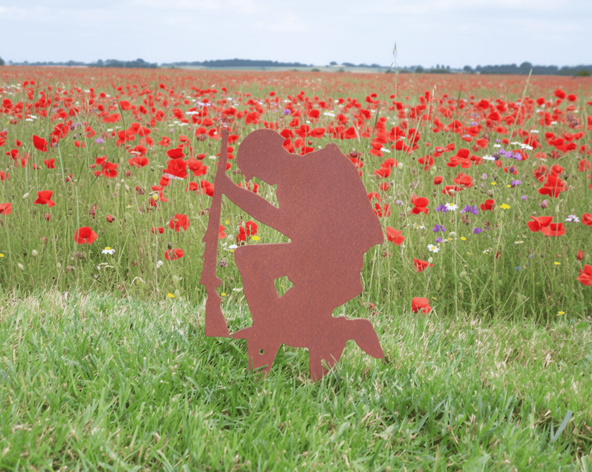 Rustic Steel SOLDIER Garden Ornament in a field of red poppies, showcasing a kneeling soldier with a rifle.