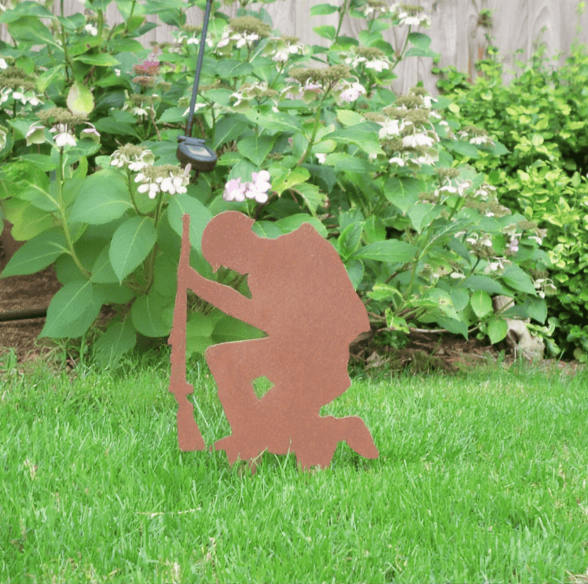 Rustic Steel SOLDIER Garden Ornament displayed in garden, featuring a kneeling soldier silhouette with rifle.