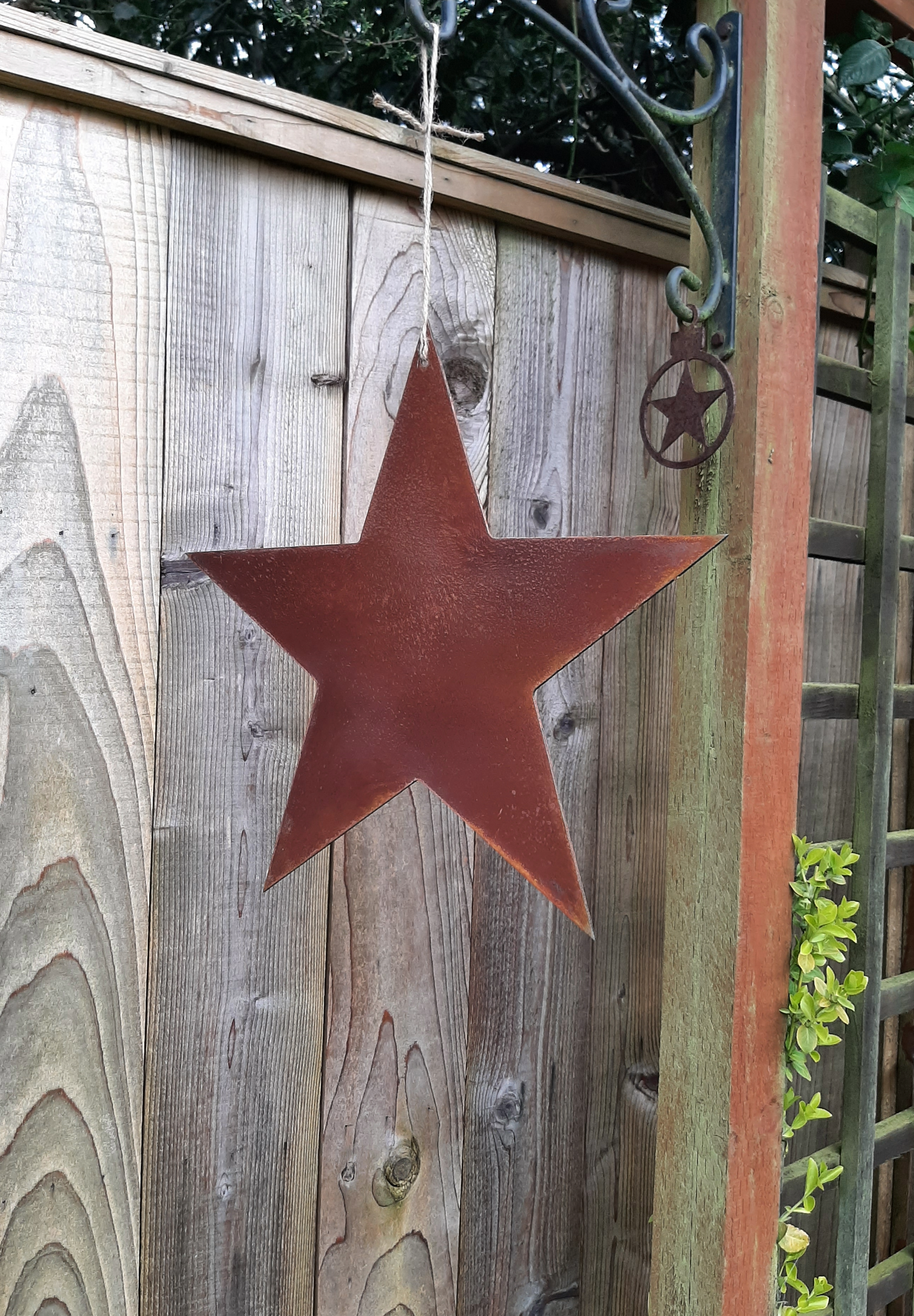 Rusty Metal STAR Garden Ornament decoration hanging on a wooden fence