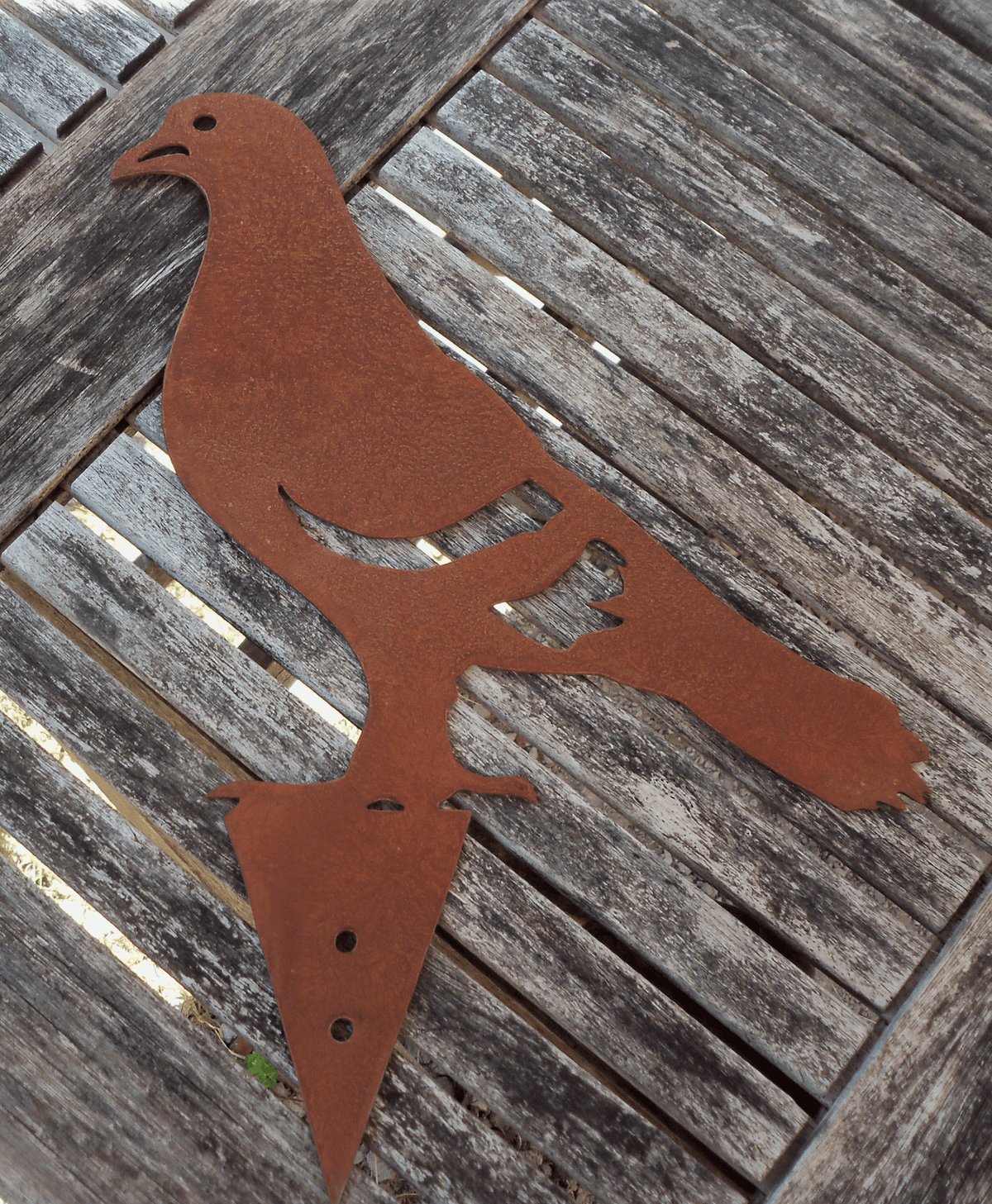 Rusty Steel PIGEON Garden Ornament on a wooden table, perfect for garden decoration or as a fence post topper.