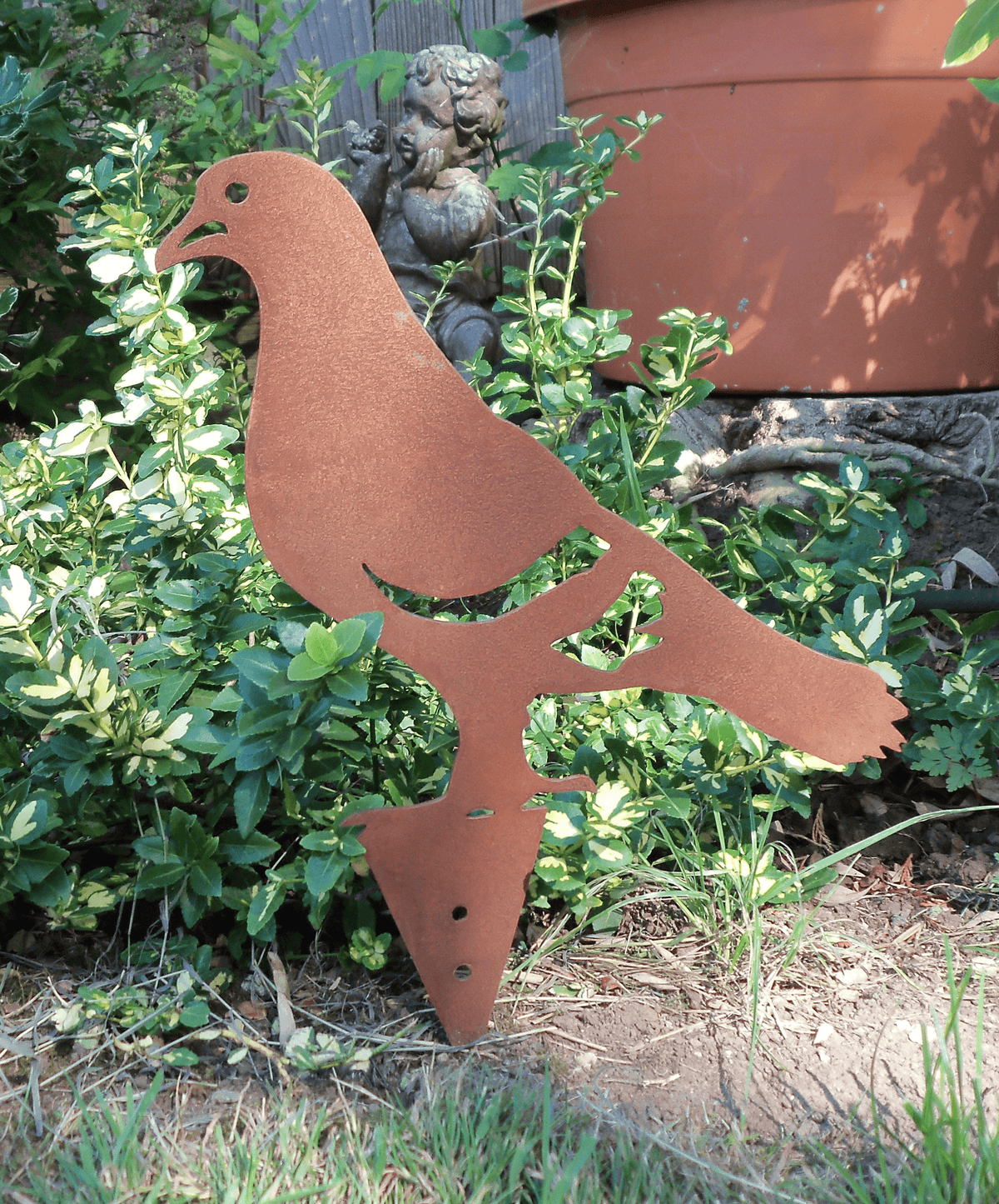 Rusty Steel PIGEON Garden Ornament in a garden setting as a ground spike decoration.
