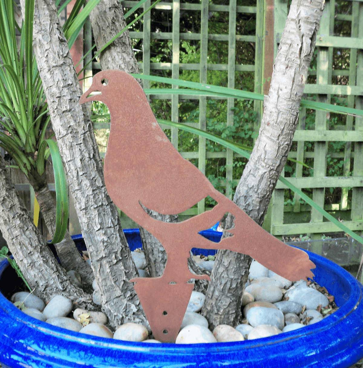 Rusty Steel PIGEON Garden Ornament in a blue pot with stones, showcasing rustic metal design and unique texture.