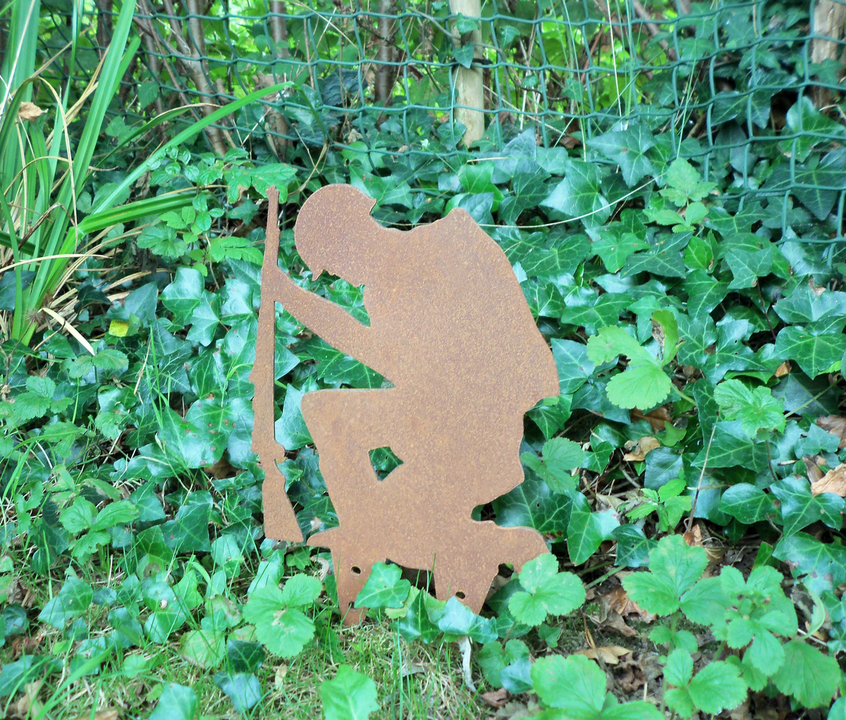 Rustic Steel SOLDIER Garden Ornament - Kneeling metal military art decoration amidst green foliage.
